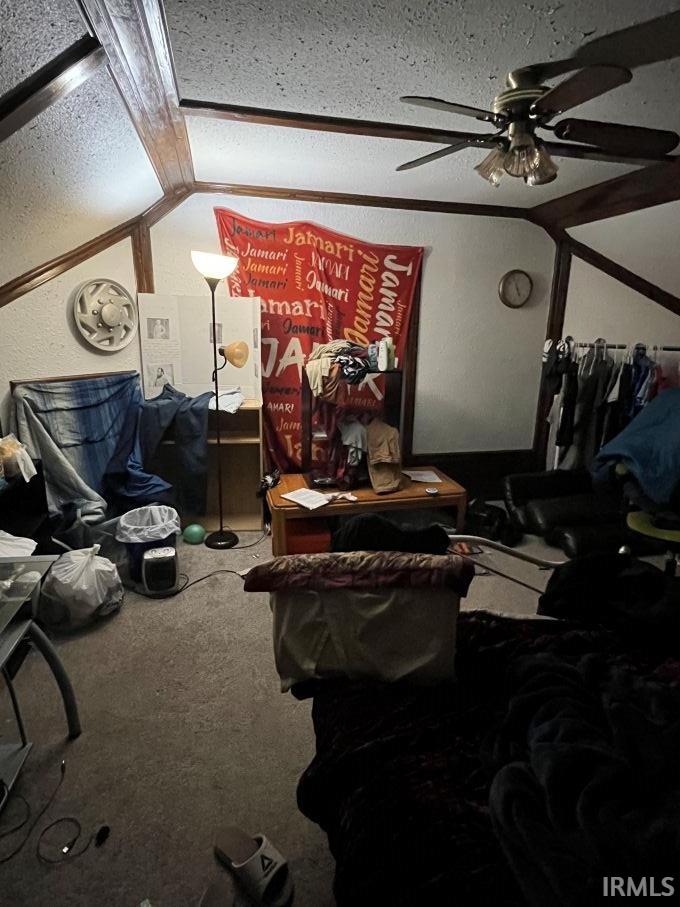 Living room with lofted ceiling, carpet floors, ceiling fan, and a textured wall