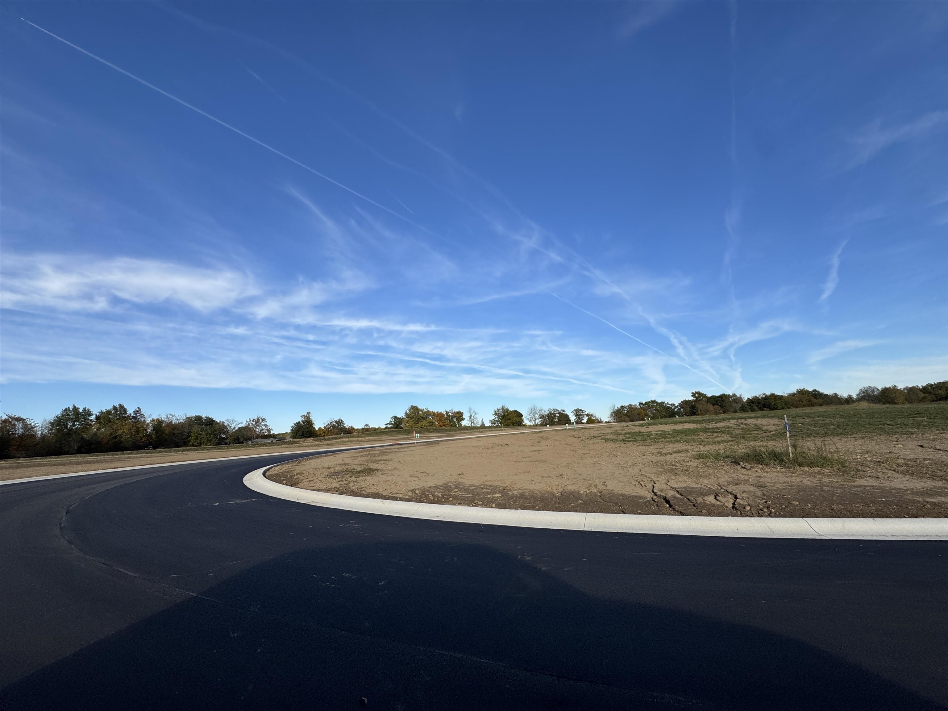 View of asphalt street with curbs and a rural view