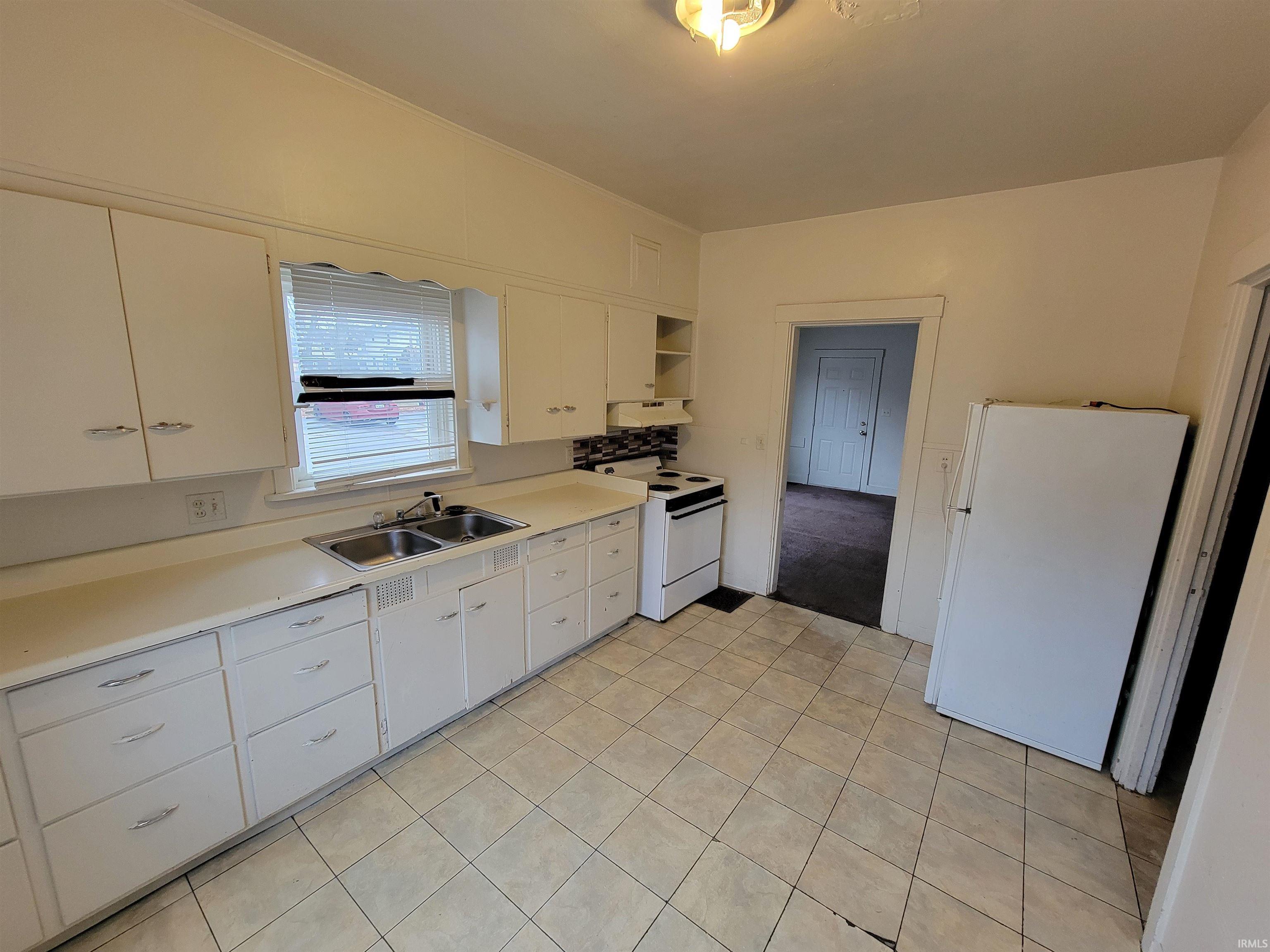 Kitchen featuring white cabinets, light countertops, white appliances, and open shelves
