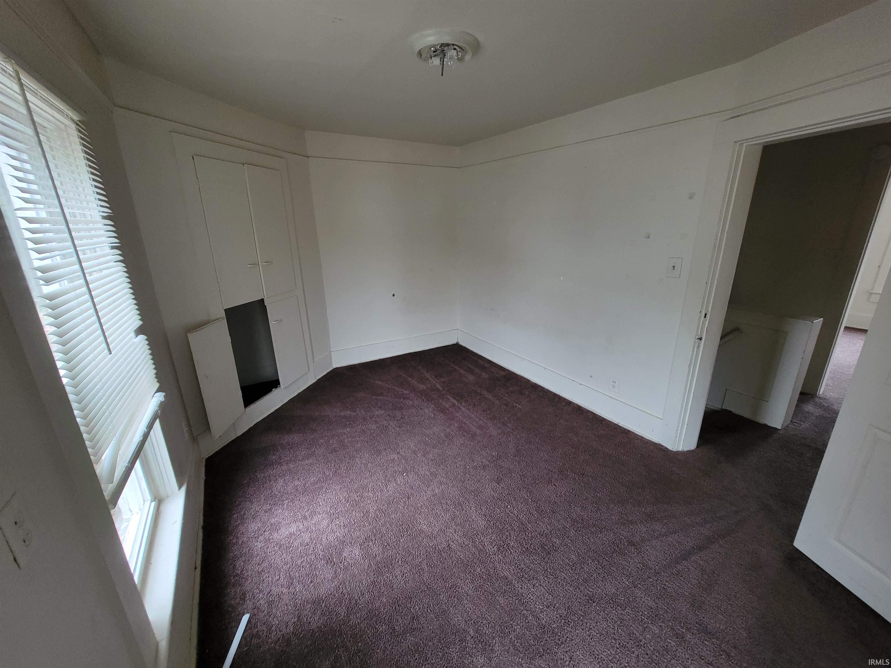 Unfurnished living room featuring healthy amount of natural light and dark carpet