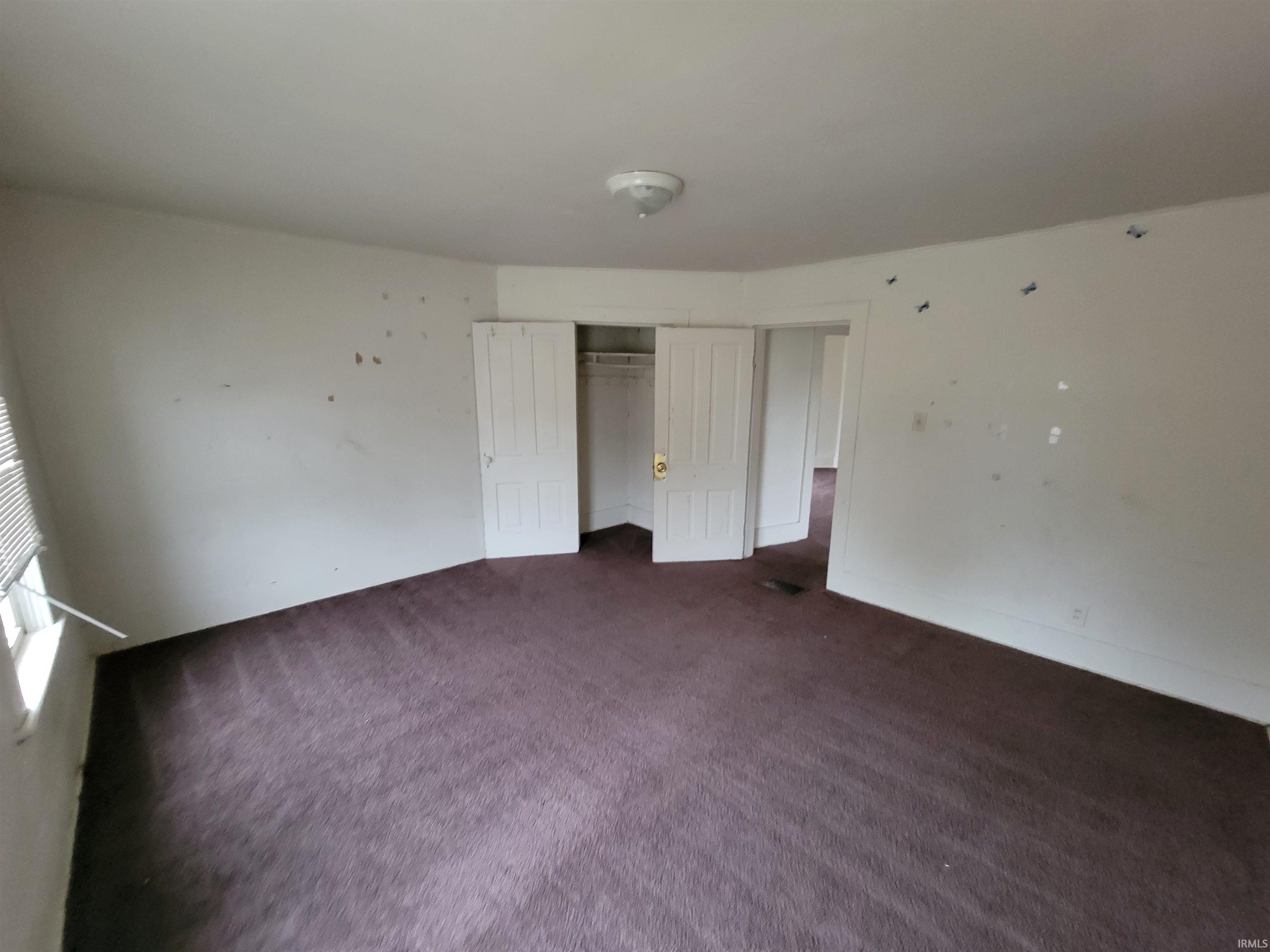 Unfurnished bedroom featuring dark colored carpet and a closet