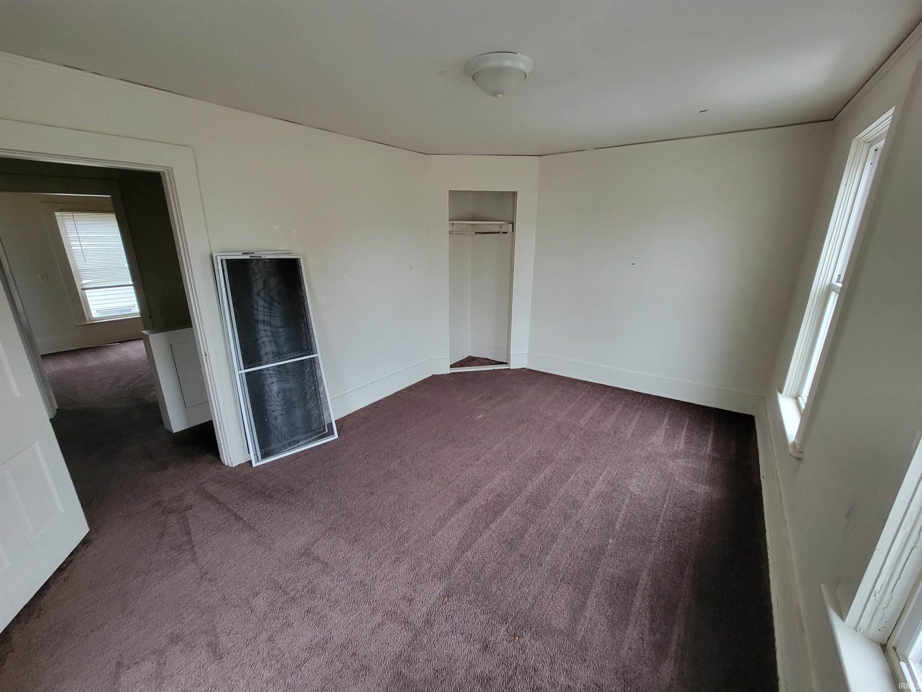 Unfurnished bedroom featuring dark colored carpet, a heating unit, and a closet