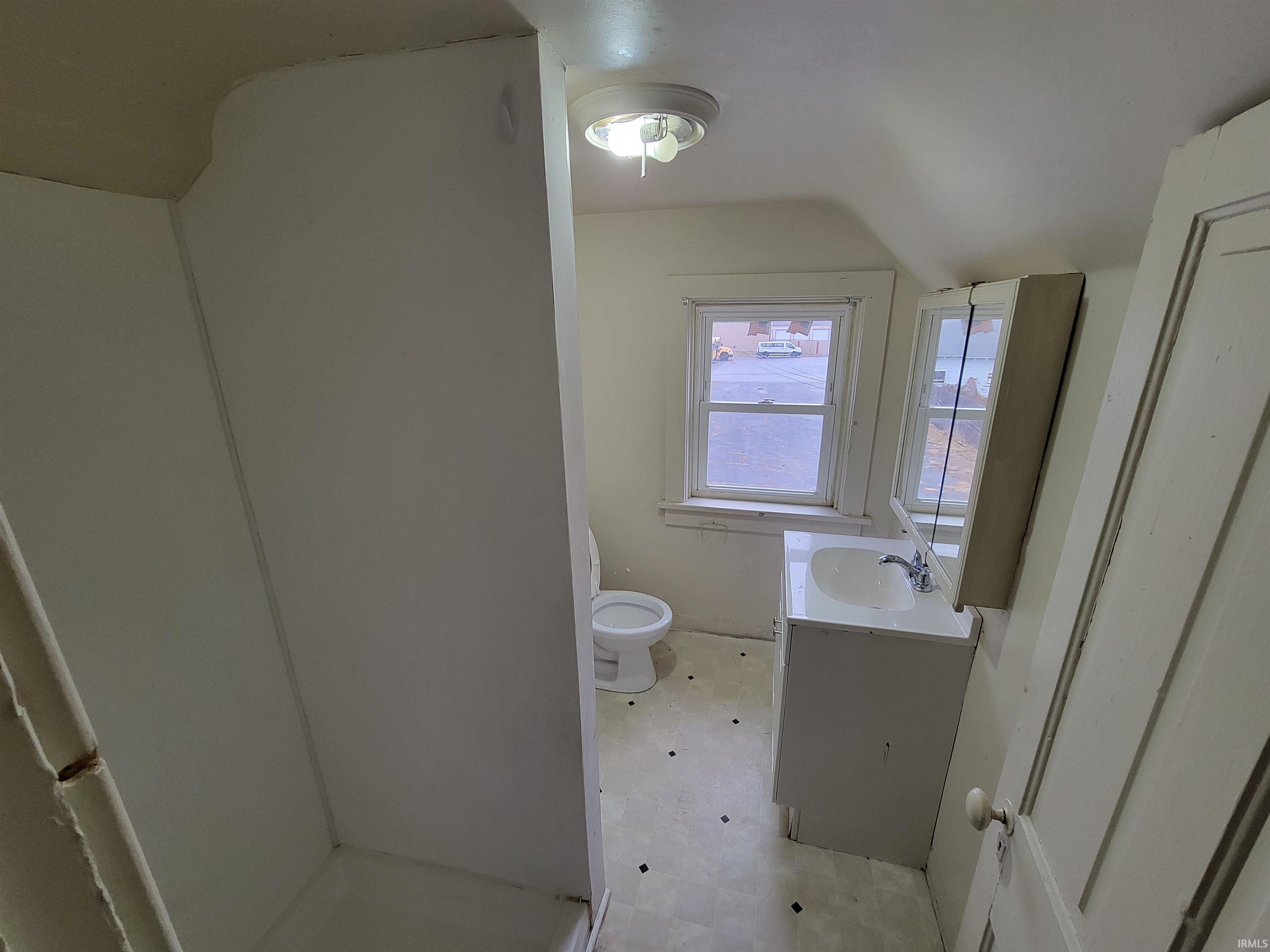 Full bathroom with vanity, a stall shower, and lofted ceiling