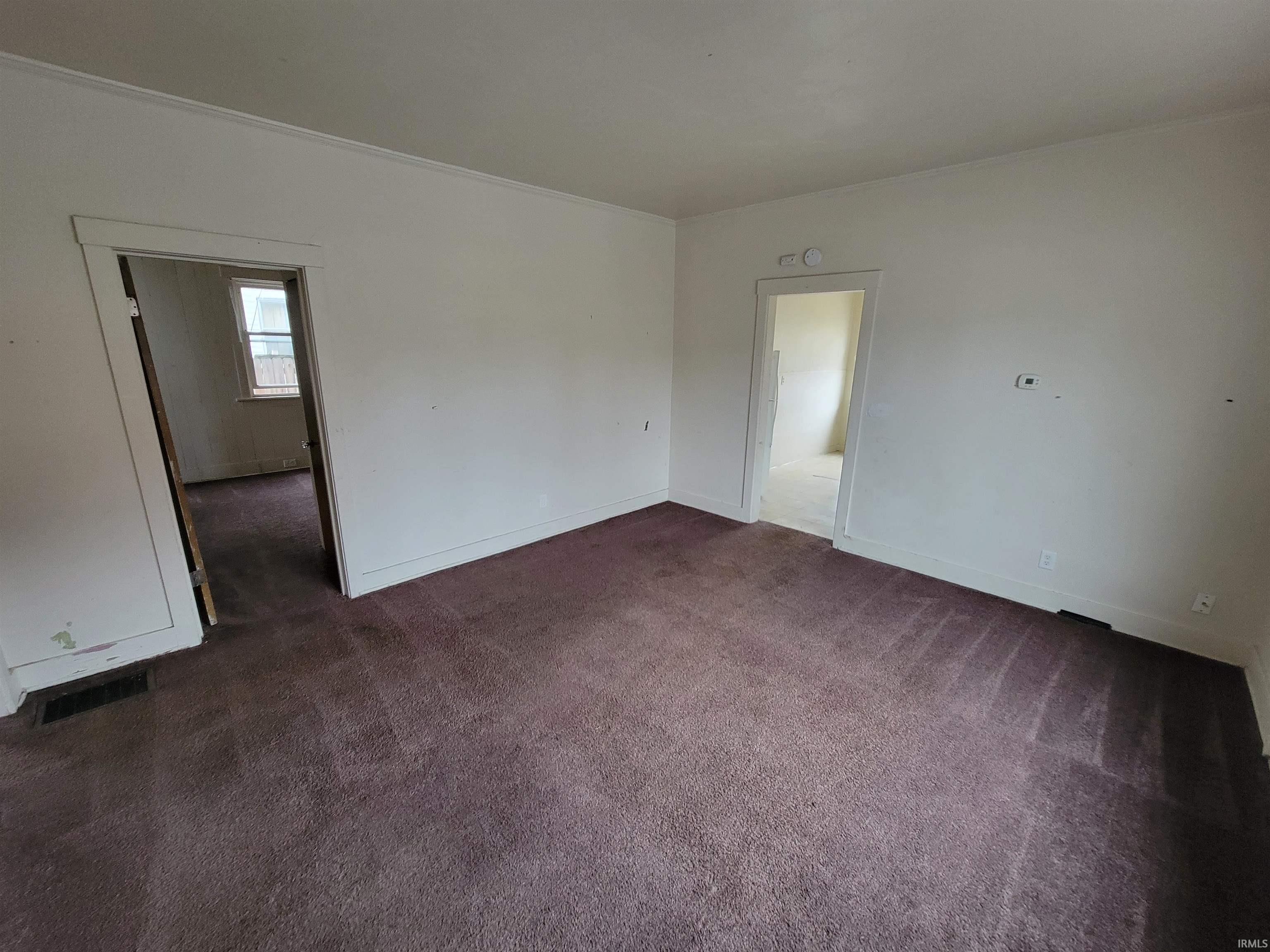 Spare room featuring dark colored carpet and ornamental molding