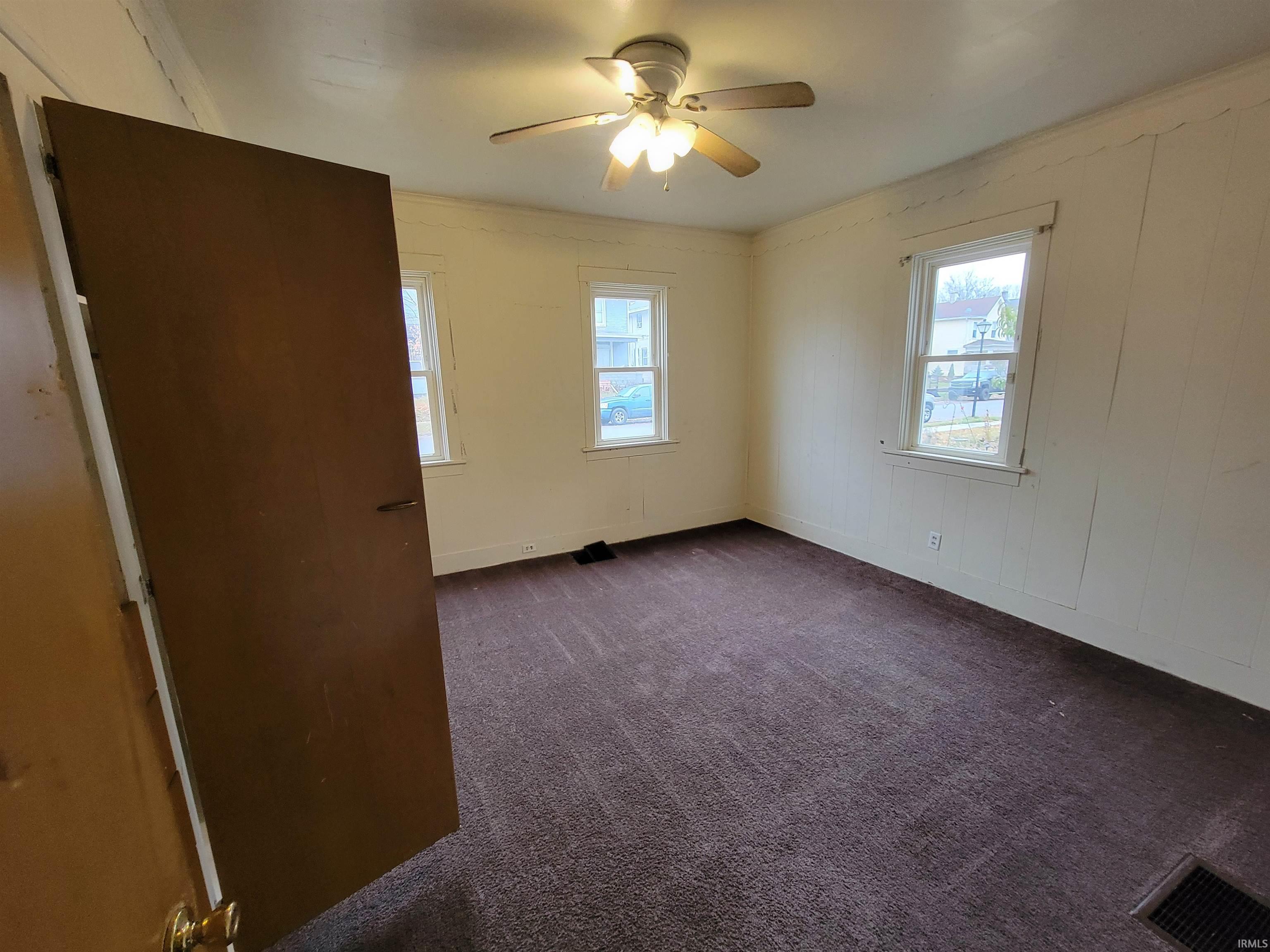 Unfurnished room featuring dark carpet and a ceiling fan