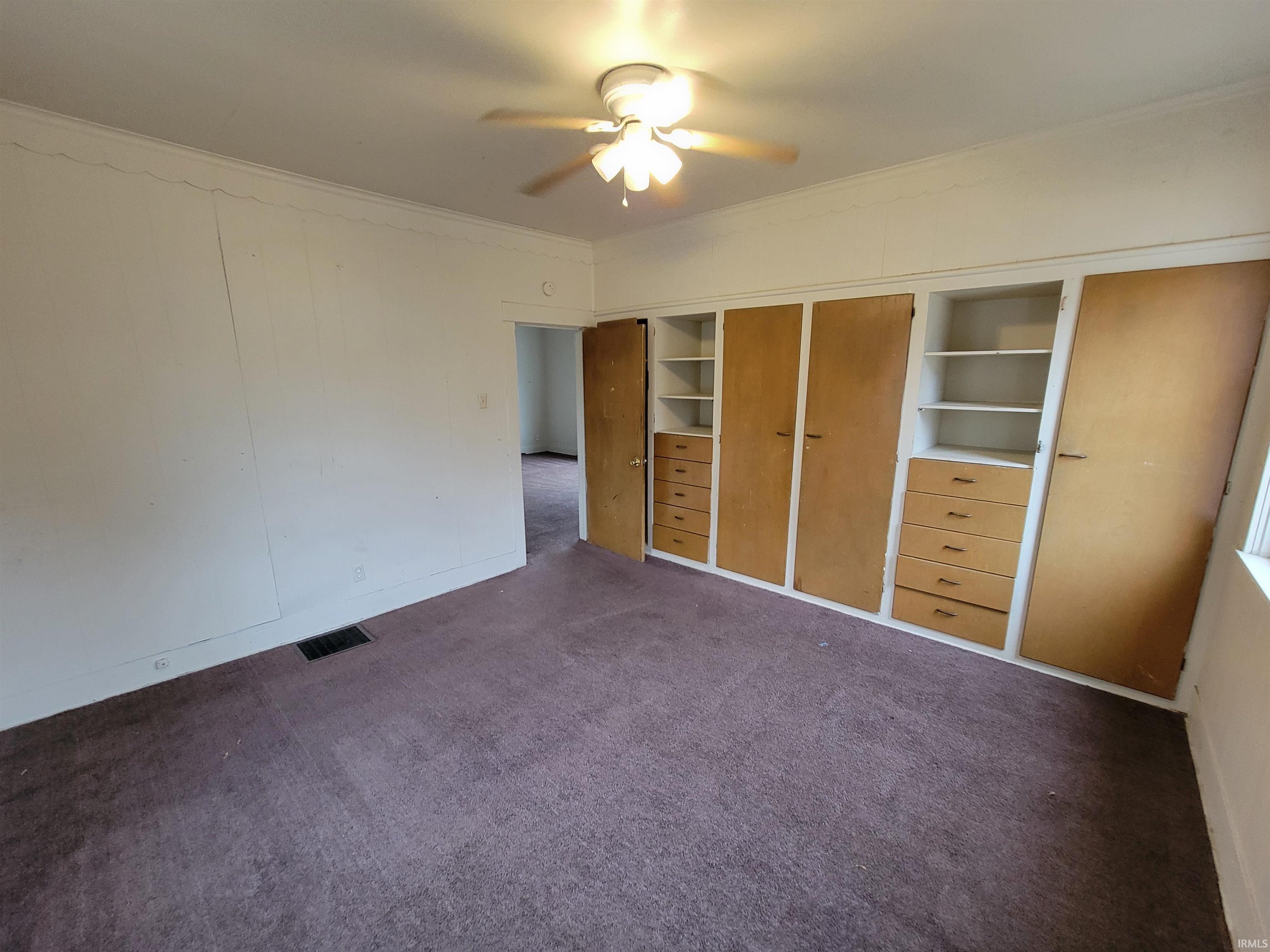 Unfurnished bedroom with carpet floors, ornamental molding, ceiling fan, and a closet