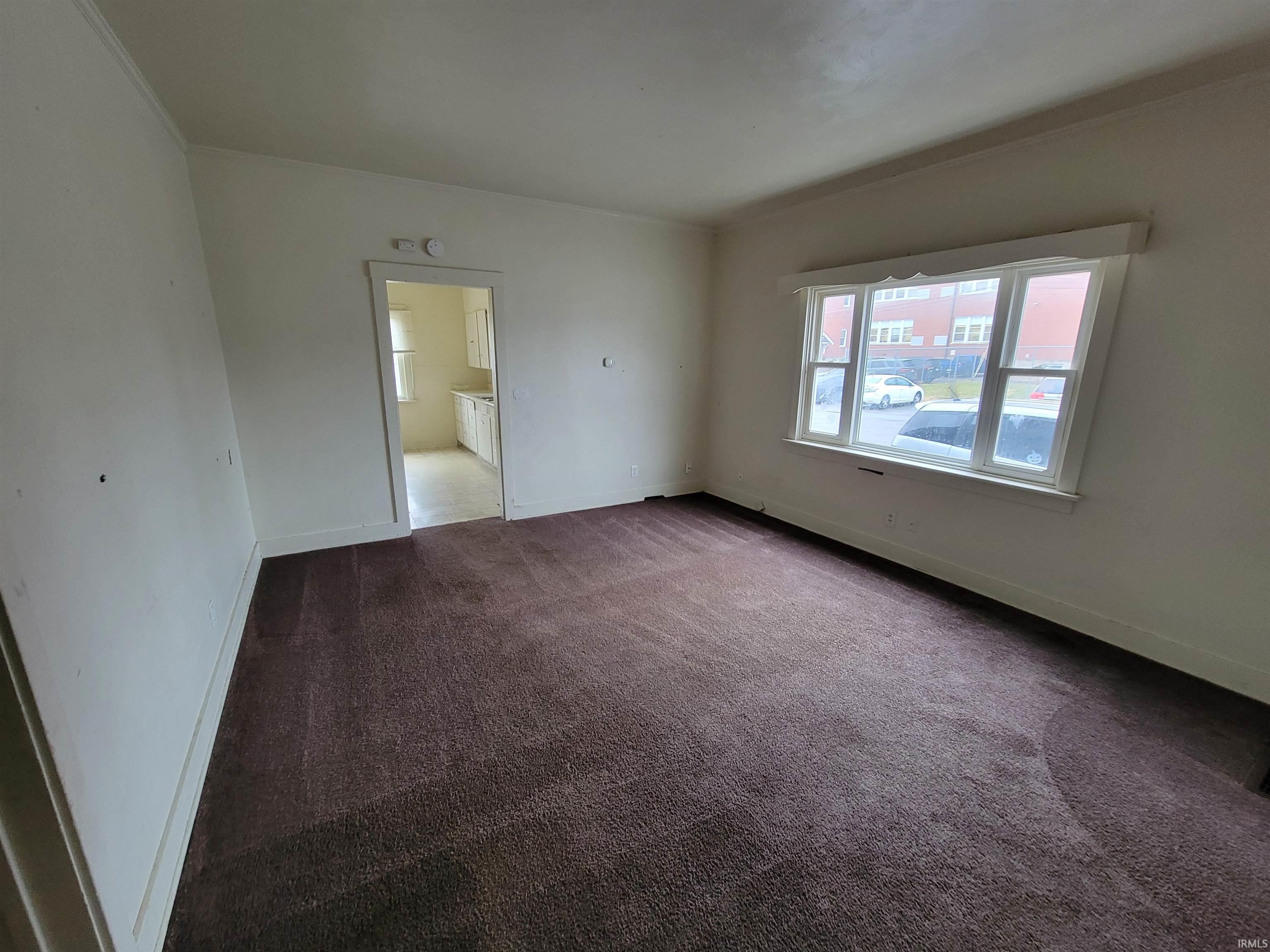 Spare room featuring dark colored carpet and ornamental molding