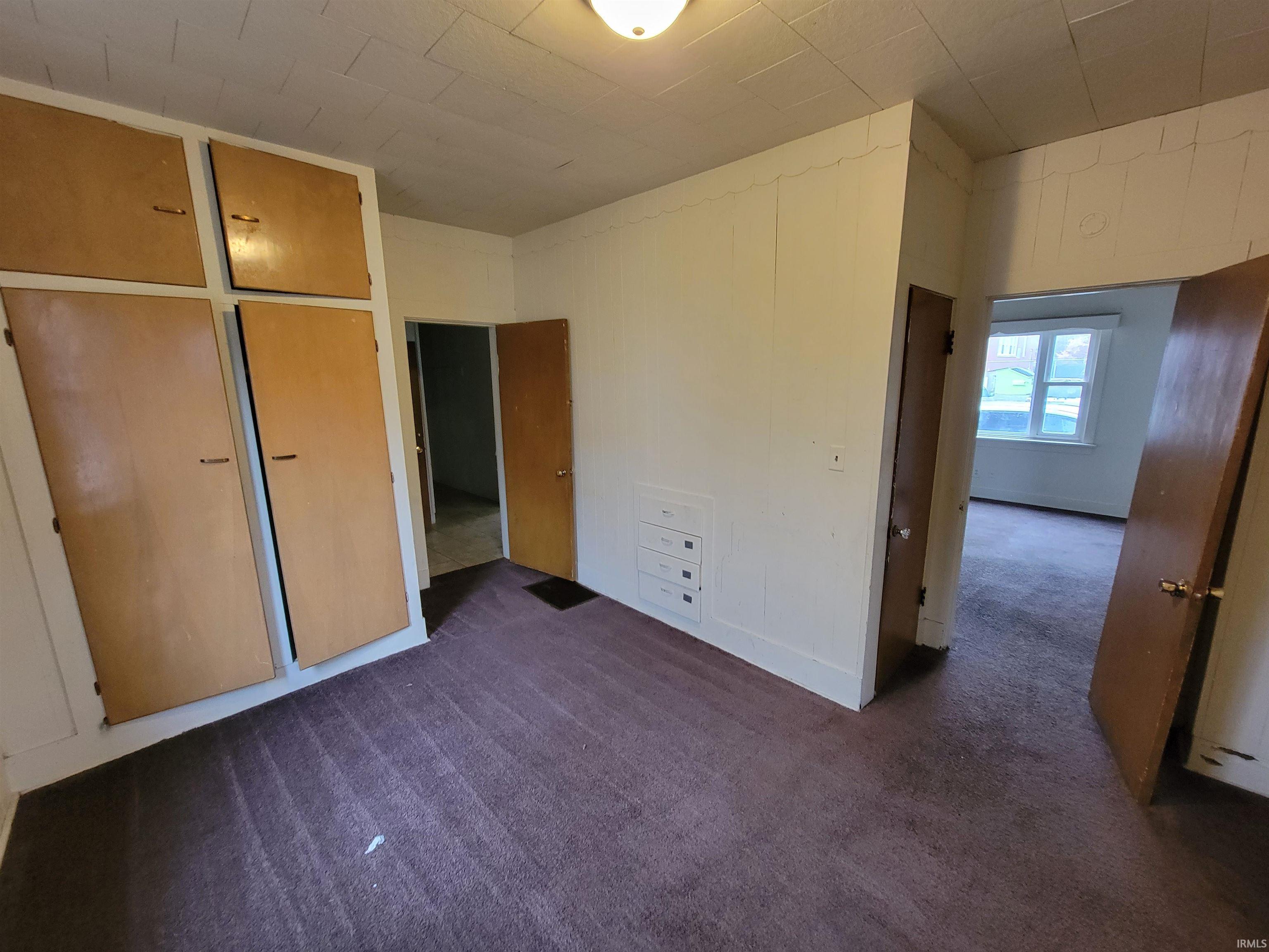 Unfurnished bedroom with dark carpet