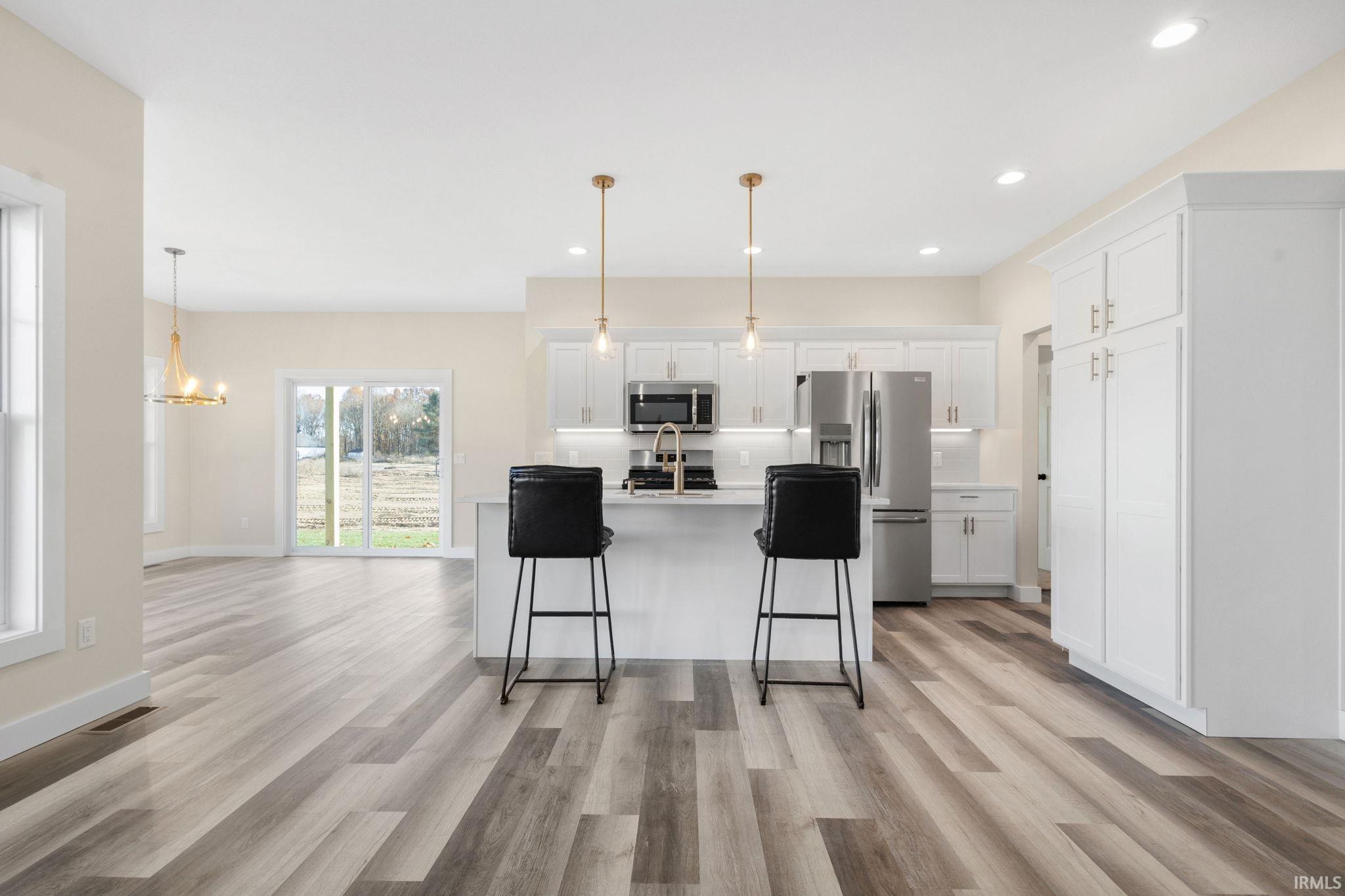 Kitchen featuring white cabinets, decorative light fixtures, stainless steel appliances, a kitchen breakfast bar, and recessed lighting