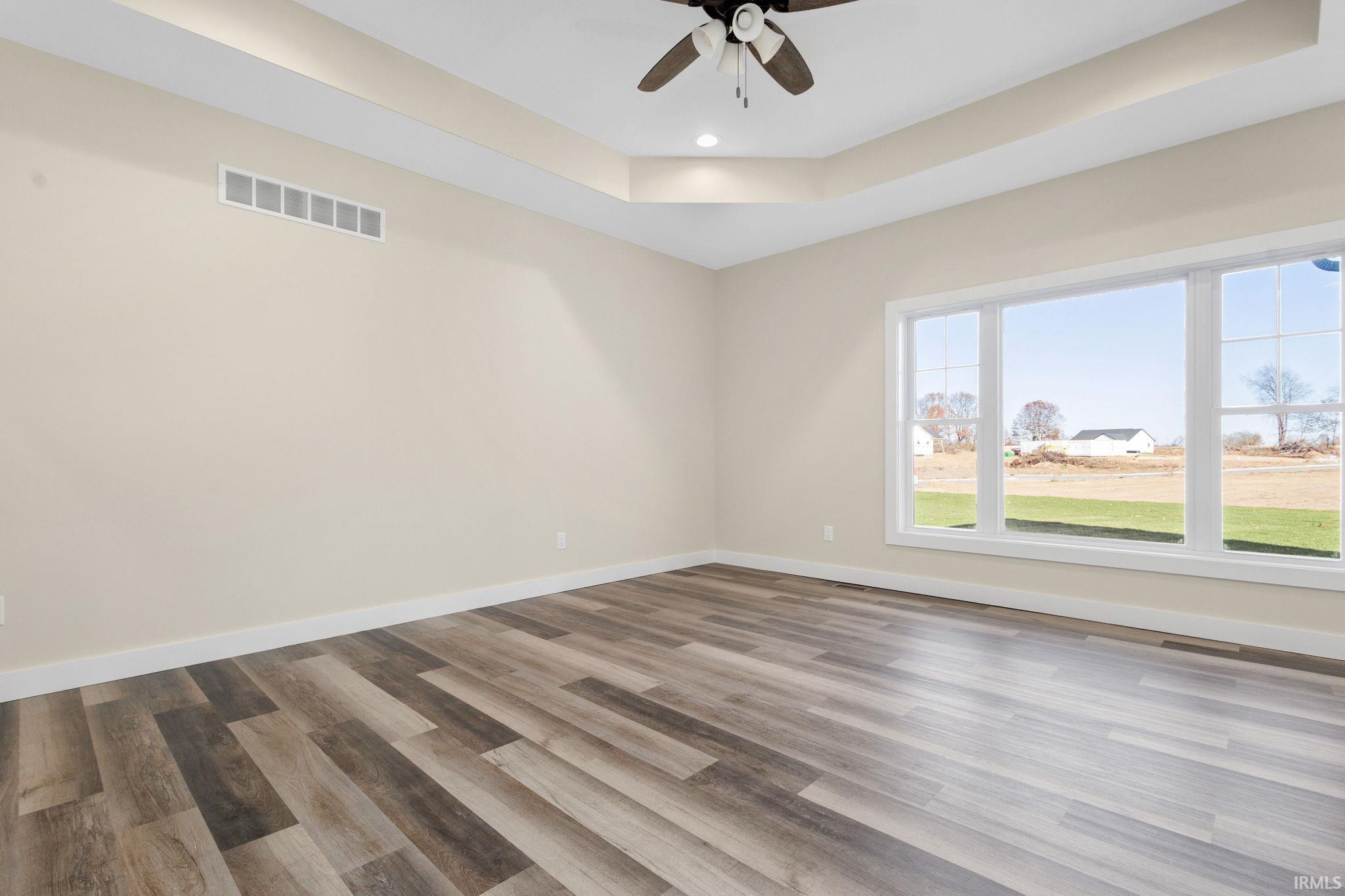 Spare room with a raised ceiling, wood finished floors, ceiling fan, and recessed lighting