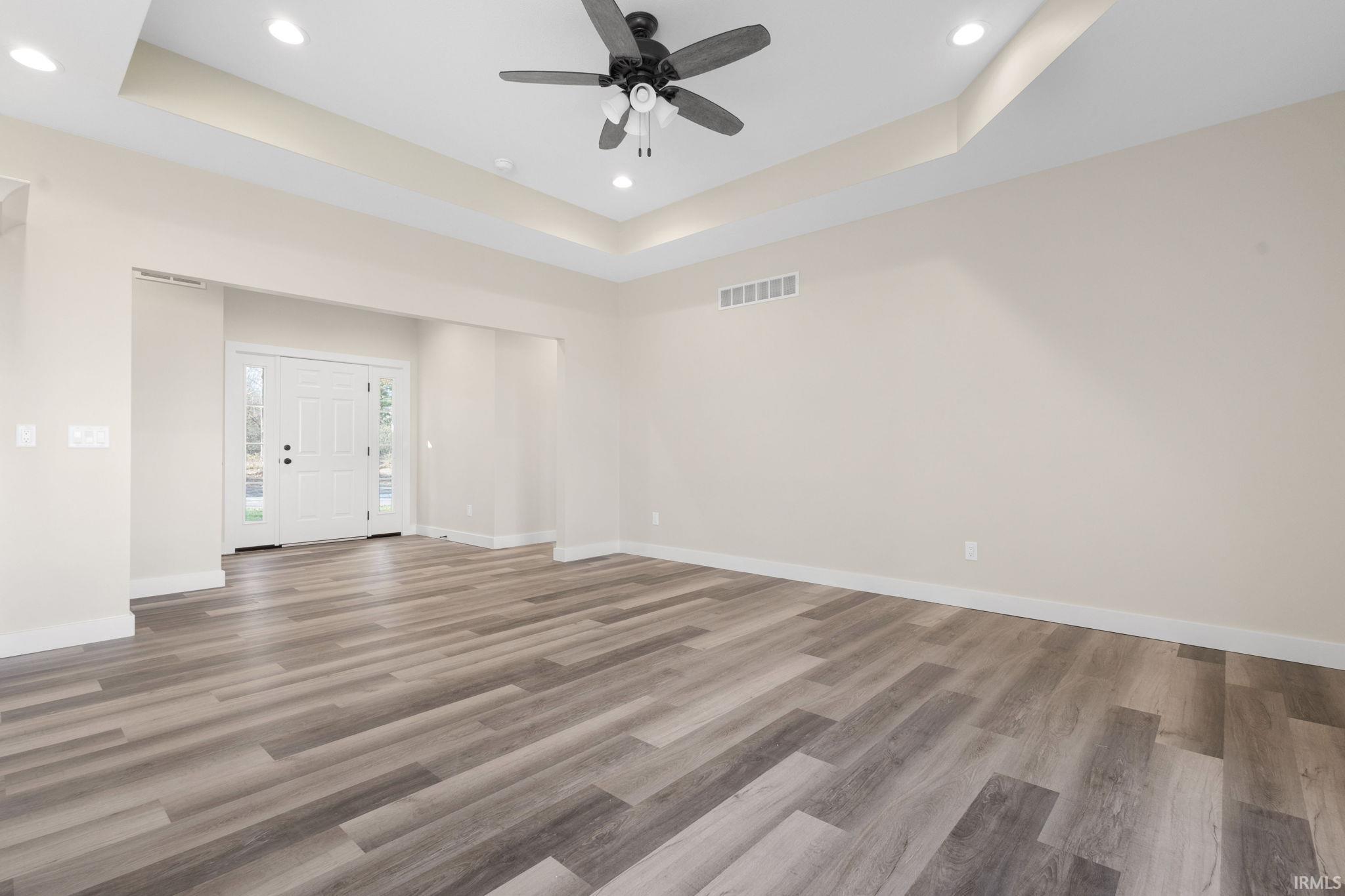 Unfurnished room featuring a raised ceiling, light wood-style floors, recessed lighting, and ceiling fan