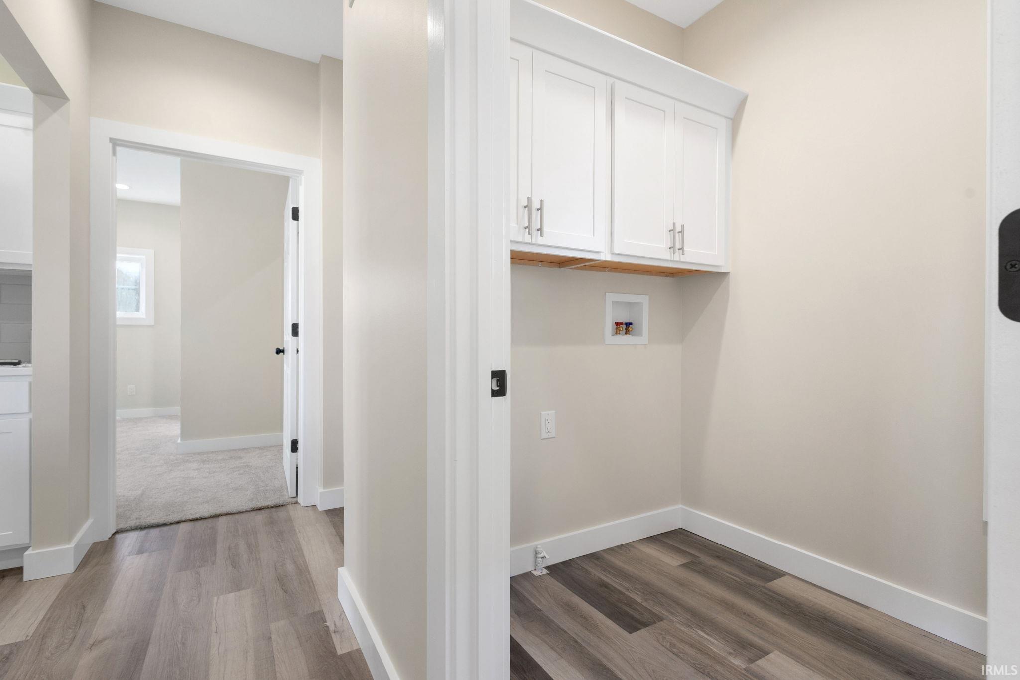 Laundry room with cabinet space, light wood-type flooring, and washer hookup