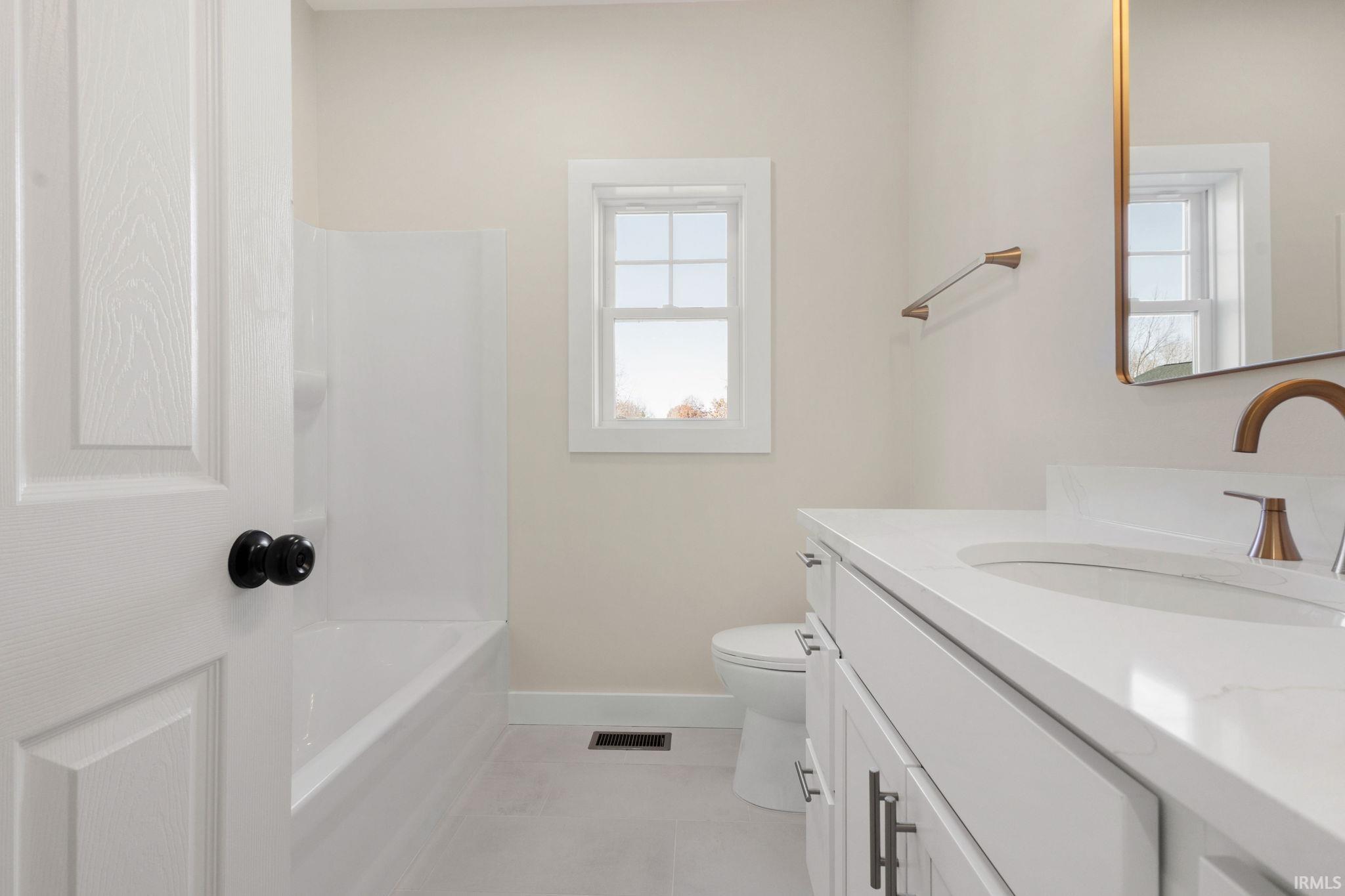 Bathroom with vanity, bathing tub / shower combination, and light tile patterned flooring