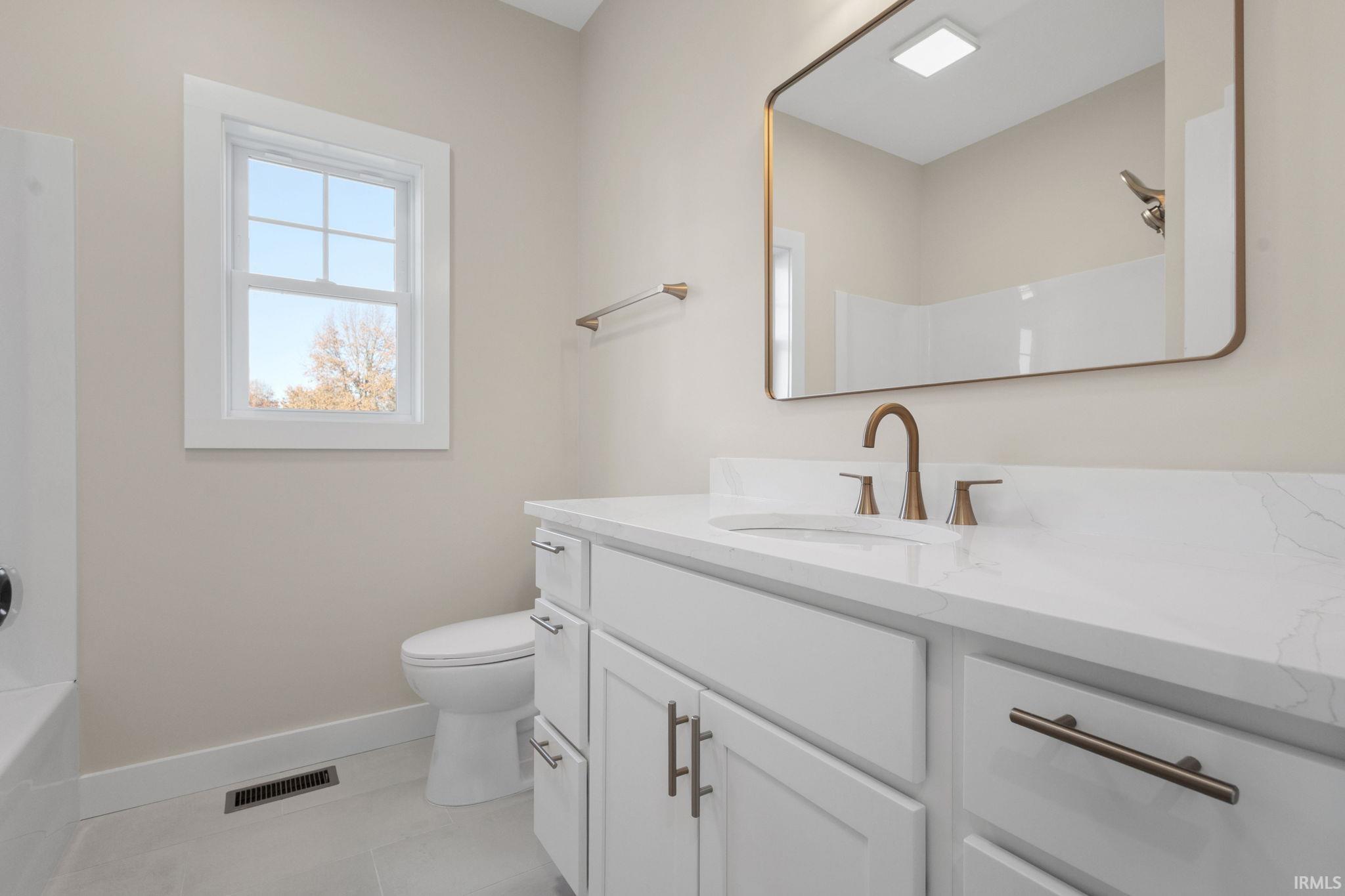 Bathroom with vanity, bathing tub / shower combination, and light tile patterned floors