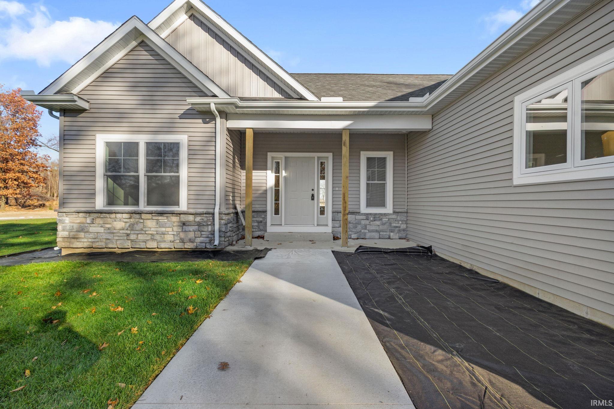 Doorway to property featuring a yard, stone siding, a porch, and board and batten siding