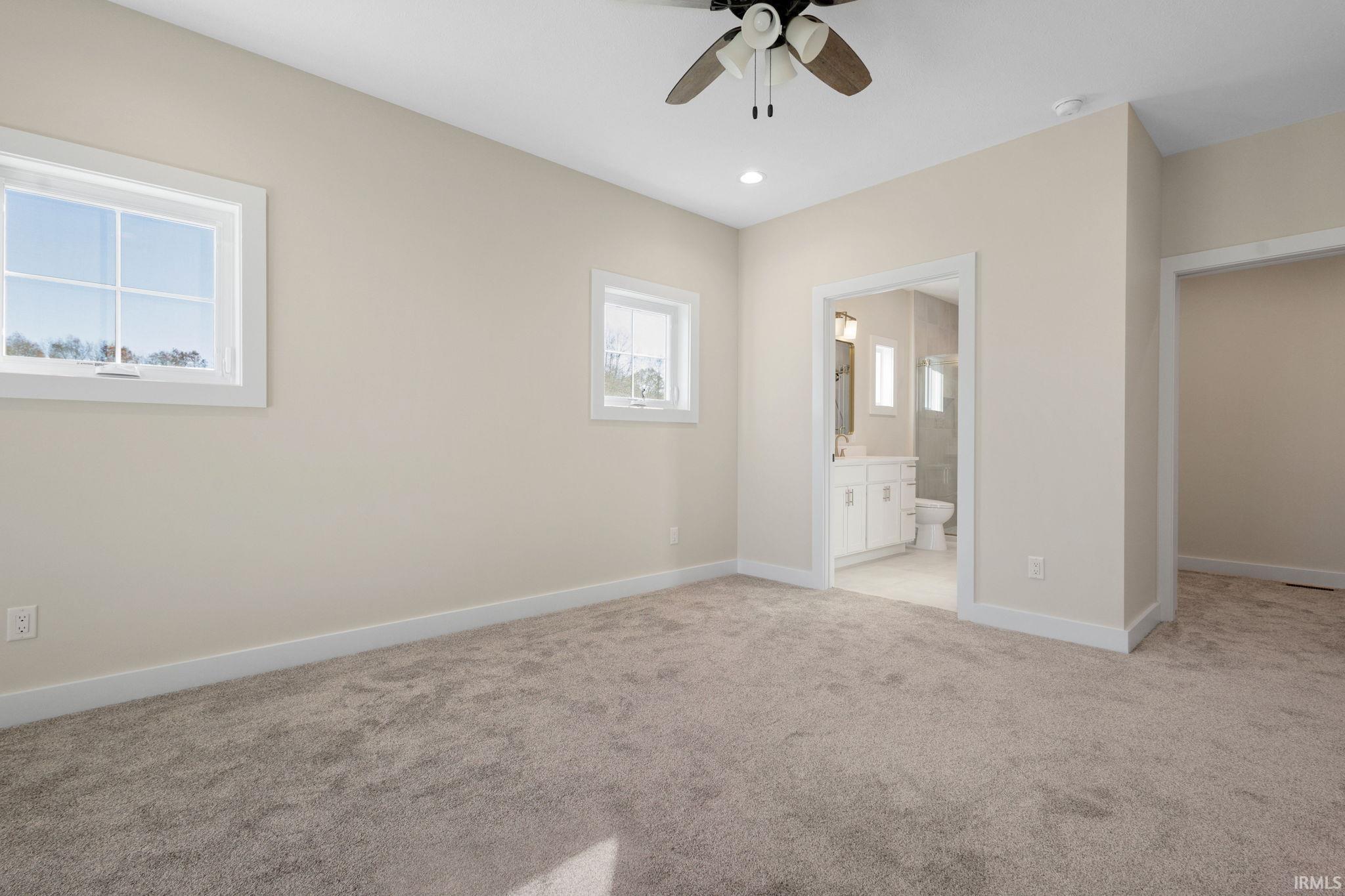 Unfurnished bedroom featuring light colored carpet, a ceiling fan, recessed lighting, and ensuite bath