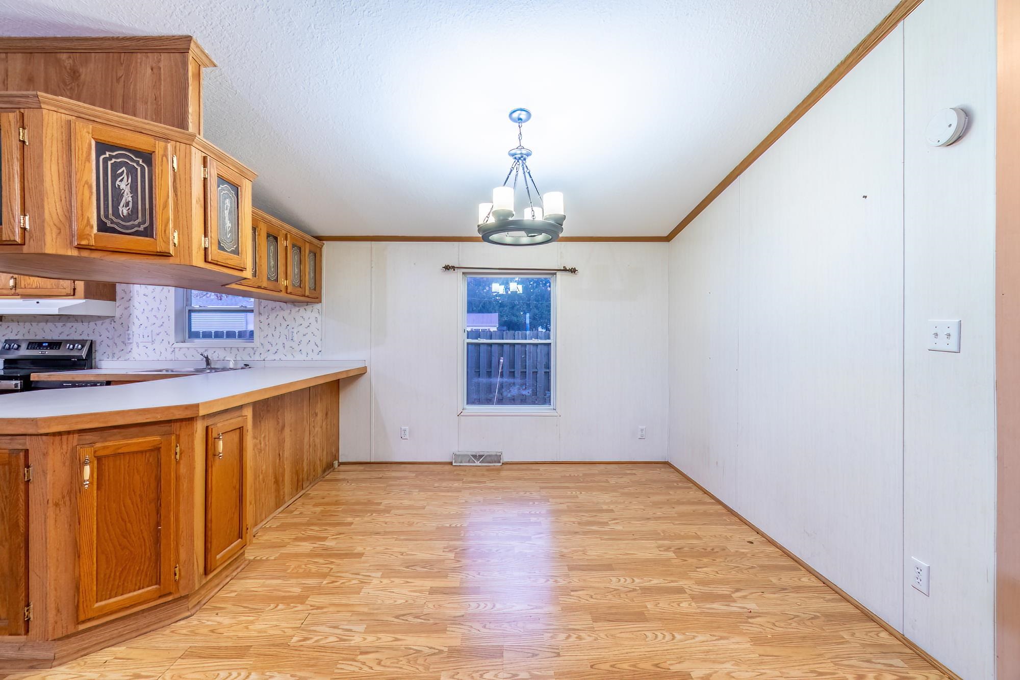 Kitchen featuring brown cabinets, light wood-type flooring, light countertops, ornamental molding, and a peninsula