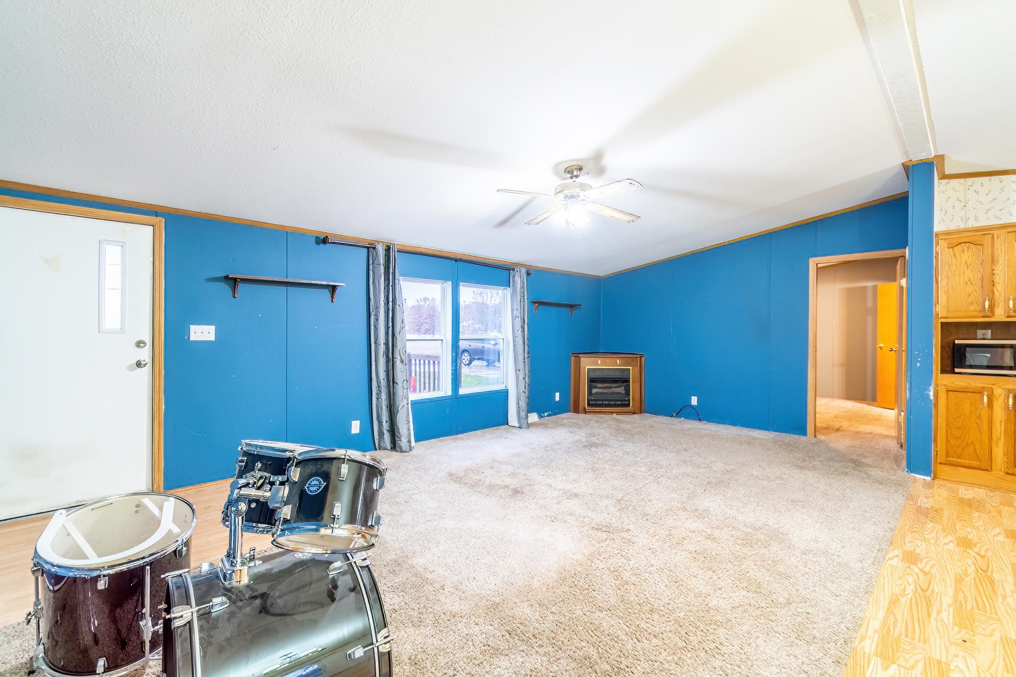 Unfurnished living room featuring crown molding, light colored carpet, vaulted ceiling, and ceiling fan