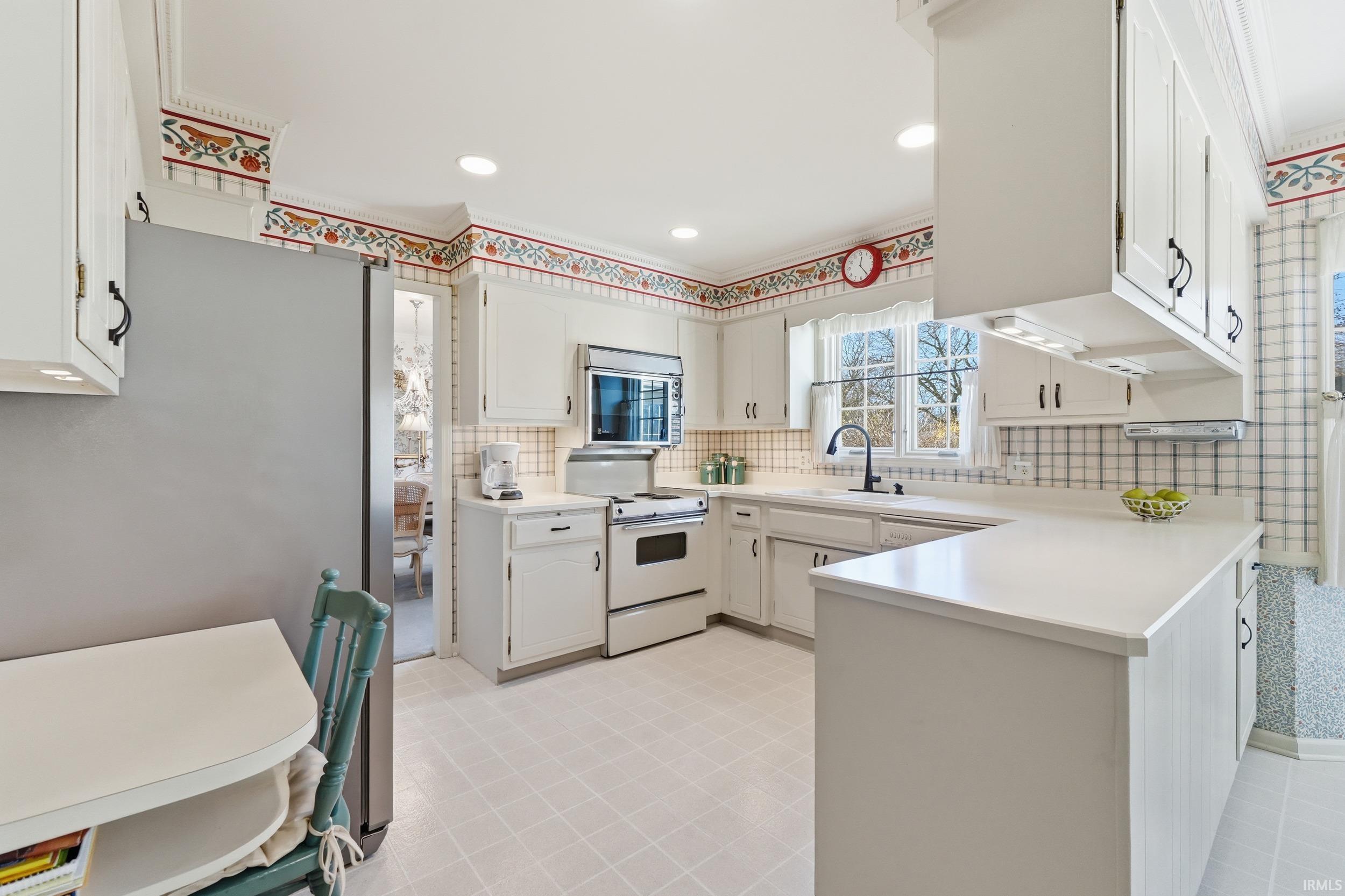 Kitchen with stainless steel appliances, decorative backsplash, light countertops, a peninsula, and crown molding
