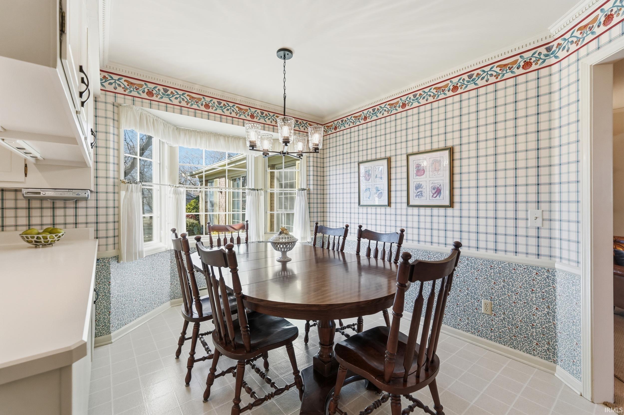 Dining room featuring wallpapered walls and a chandelier