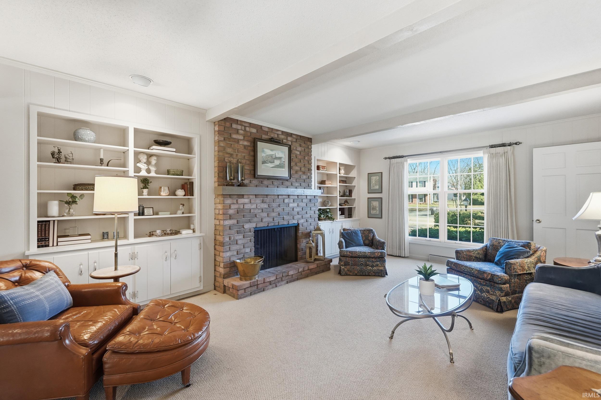 Carpeted living room featuring built in features, beamed ceiling, and a fireplace