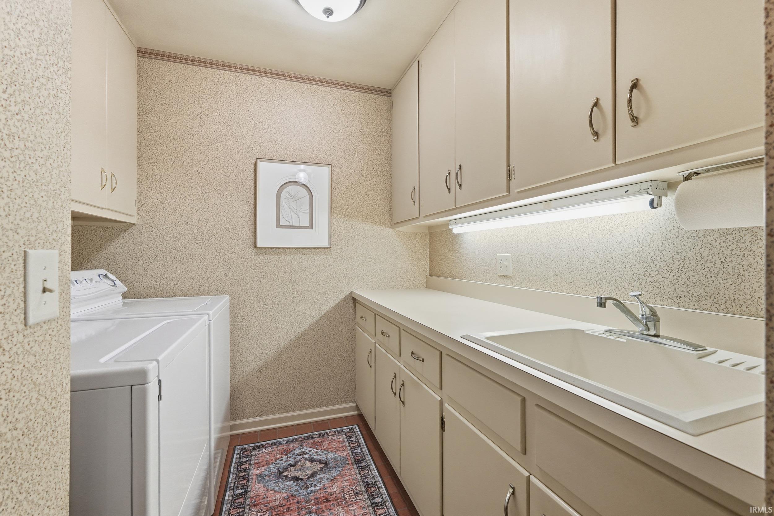 Laundry room featuring independent washer and dryer, cabinet space, crown molding, and wallpapered walls