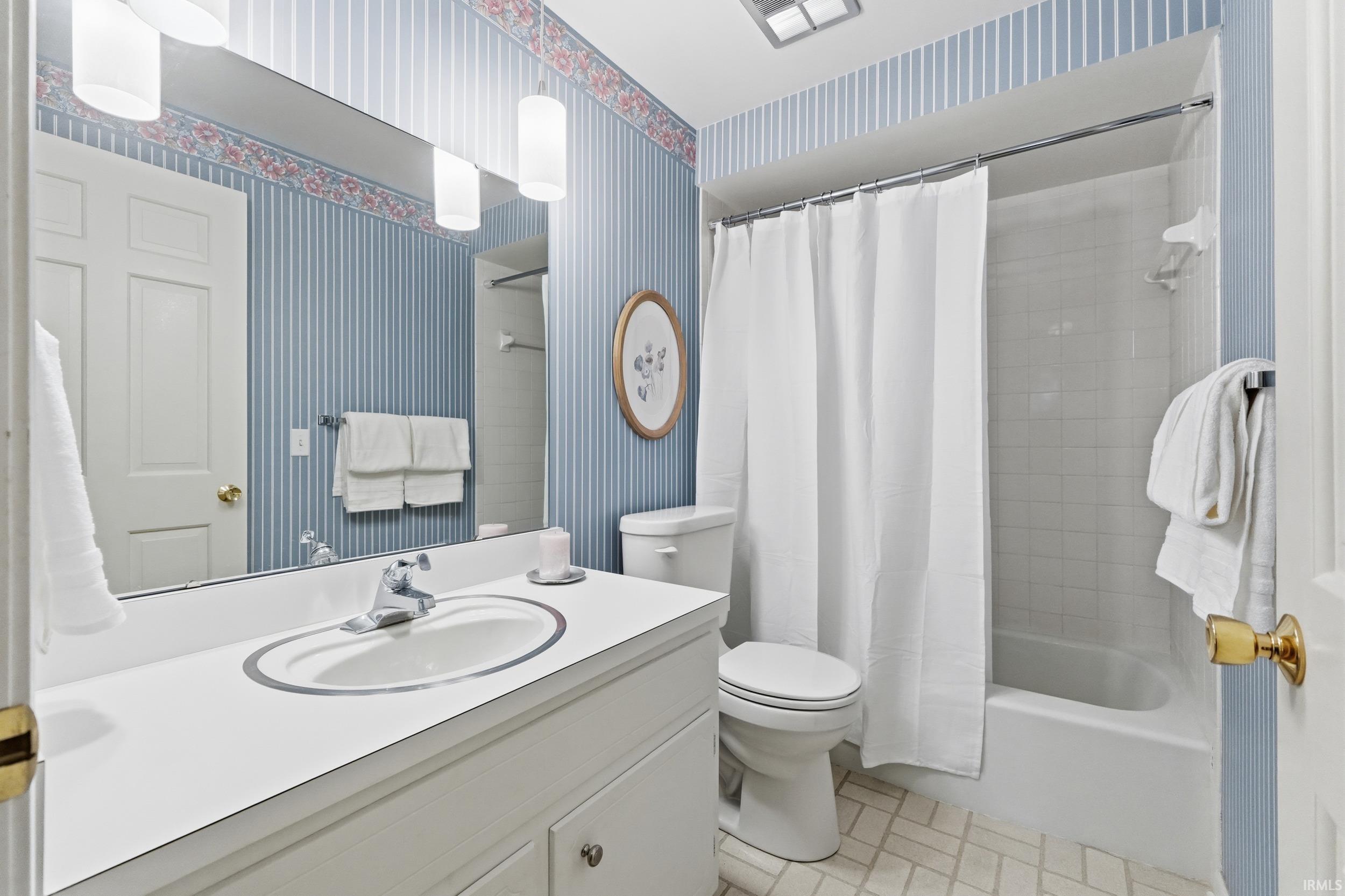 Bathroom featuring wallpapered walls, vanity, shower / bath combo, and light tile patterned flooring