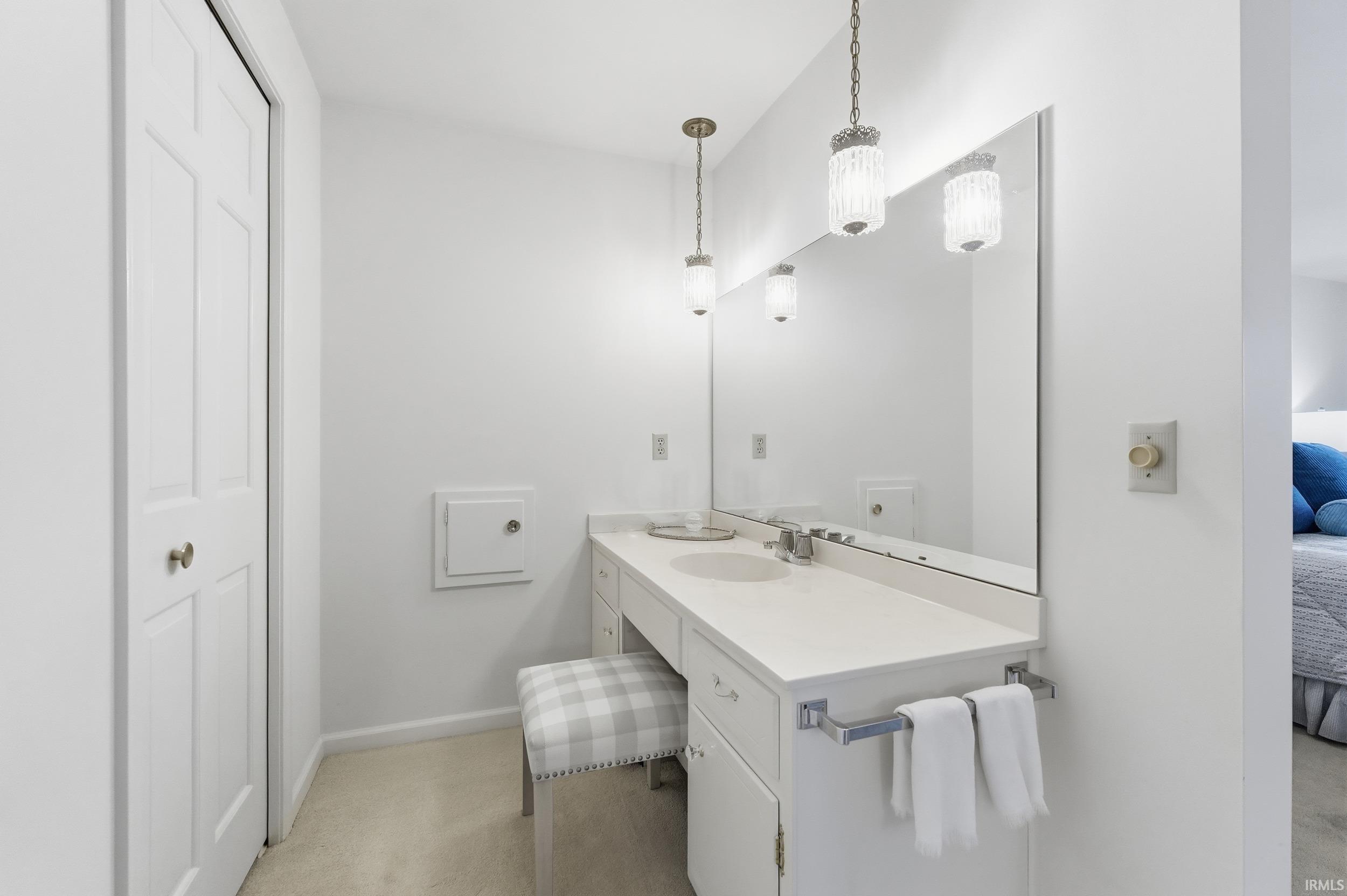 Ensuite bathroom with vanity and light carpet