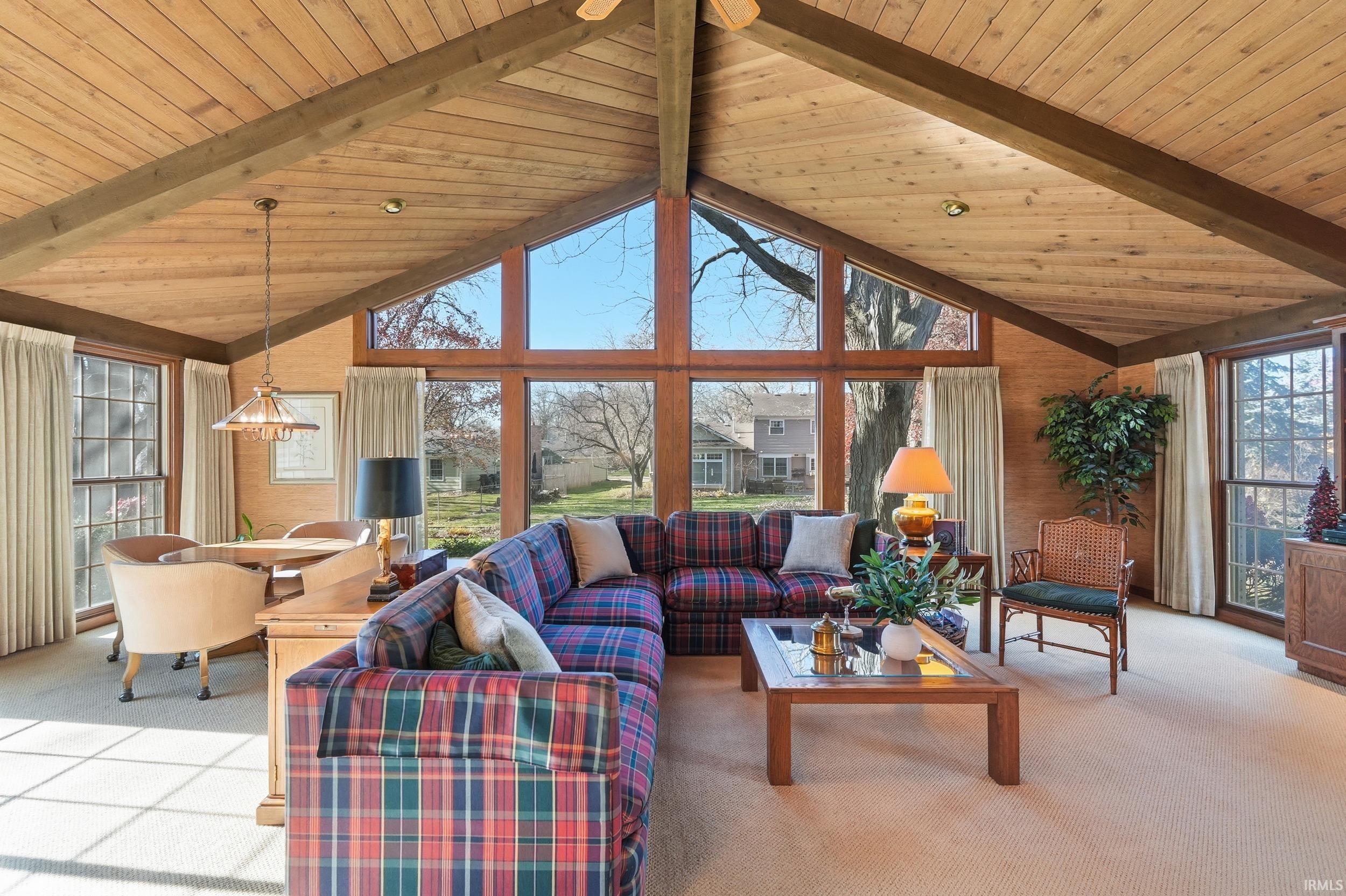 Living area with carpet flooring, high vaulted ceiling, and a wood ceiling with exposed beams