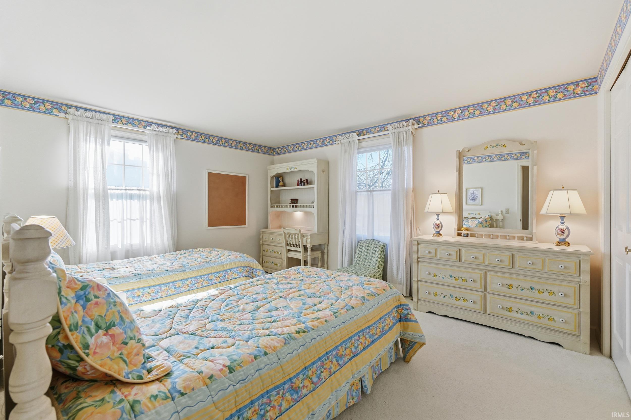 Bedroom with light carpet and multiple windows