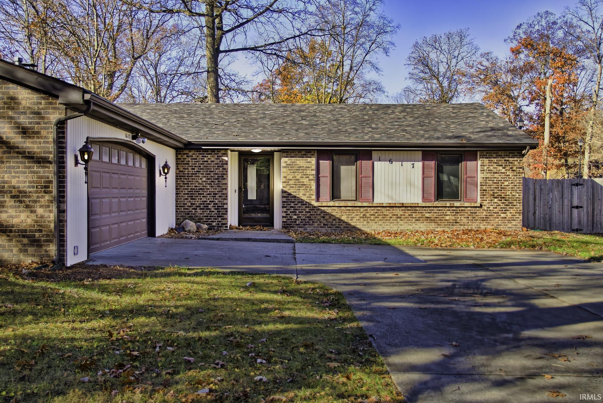Ranch-style house featuring brick siding, concrete driveway, roof with shingles, and an attached garage