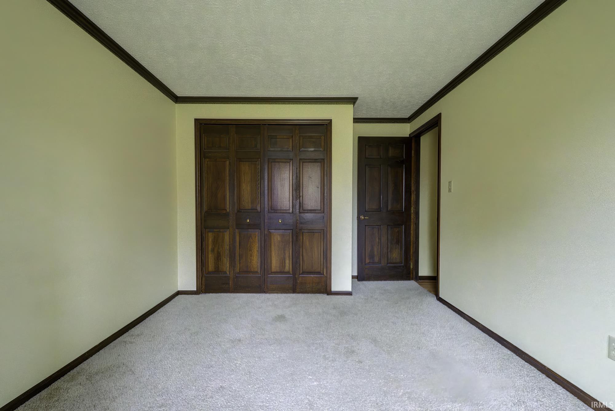 Unfurnished bedroom with carpet flooring, ornamental molding, a closet, and a textured ceiling