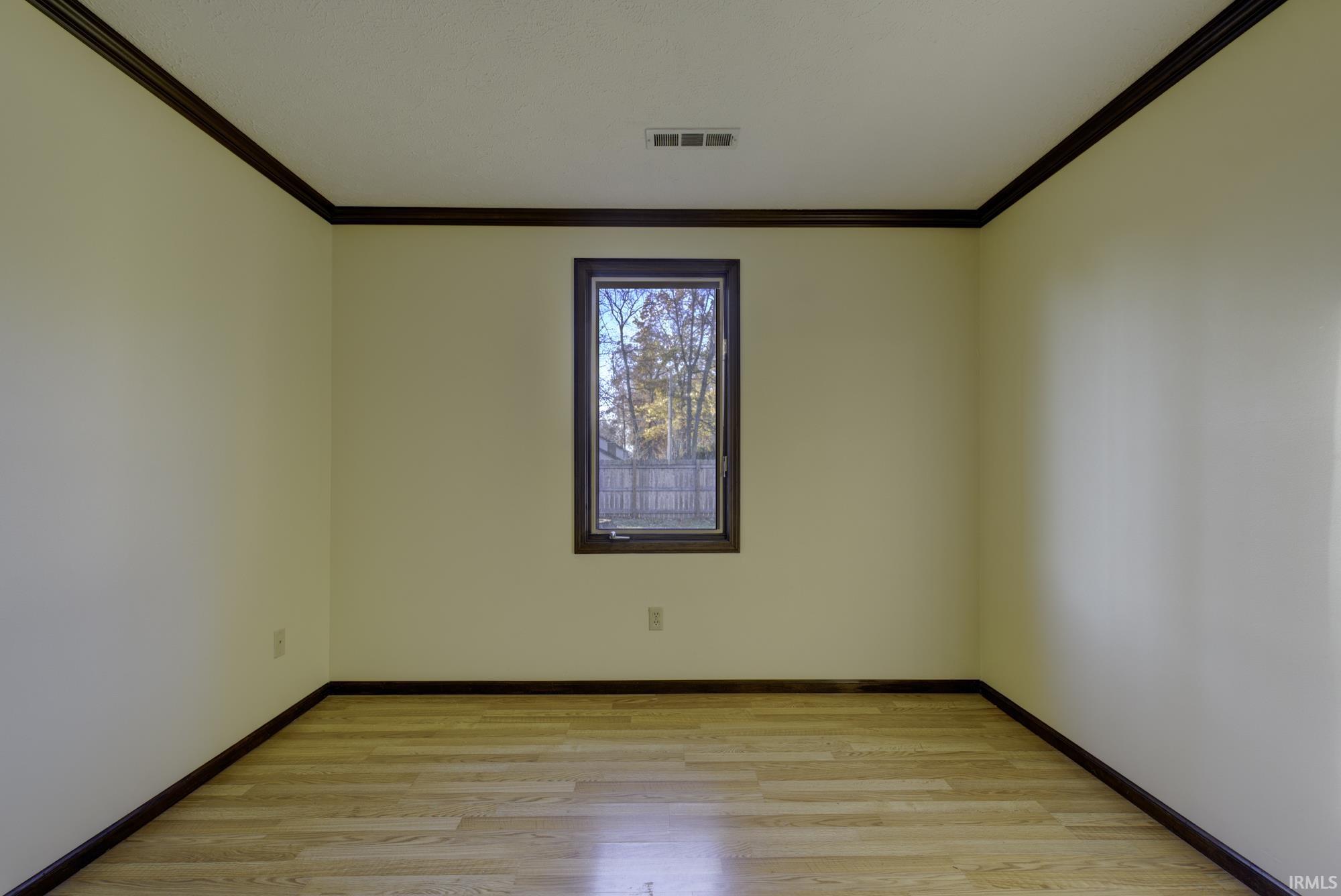 Empty room with light wood finished floors and ornamental molding