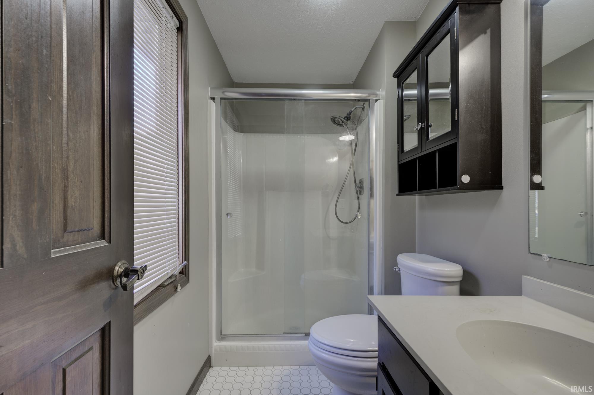 Bathroom featuring vanity, a stall shower, and light tile patterned flooring