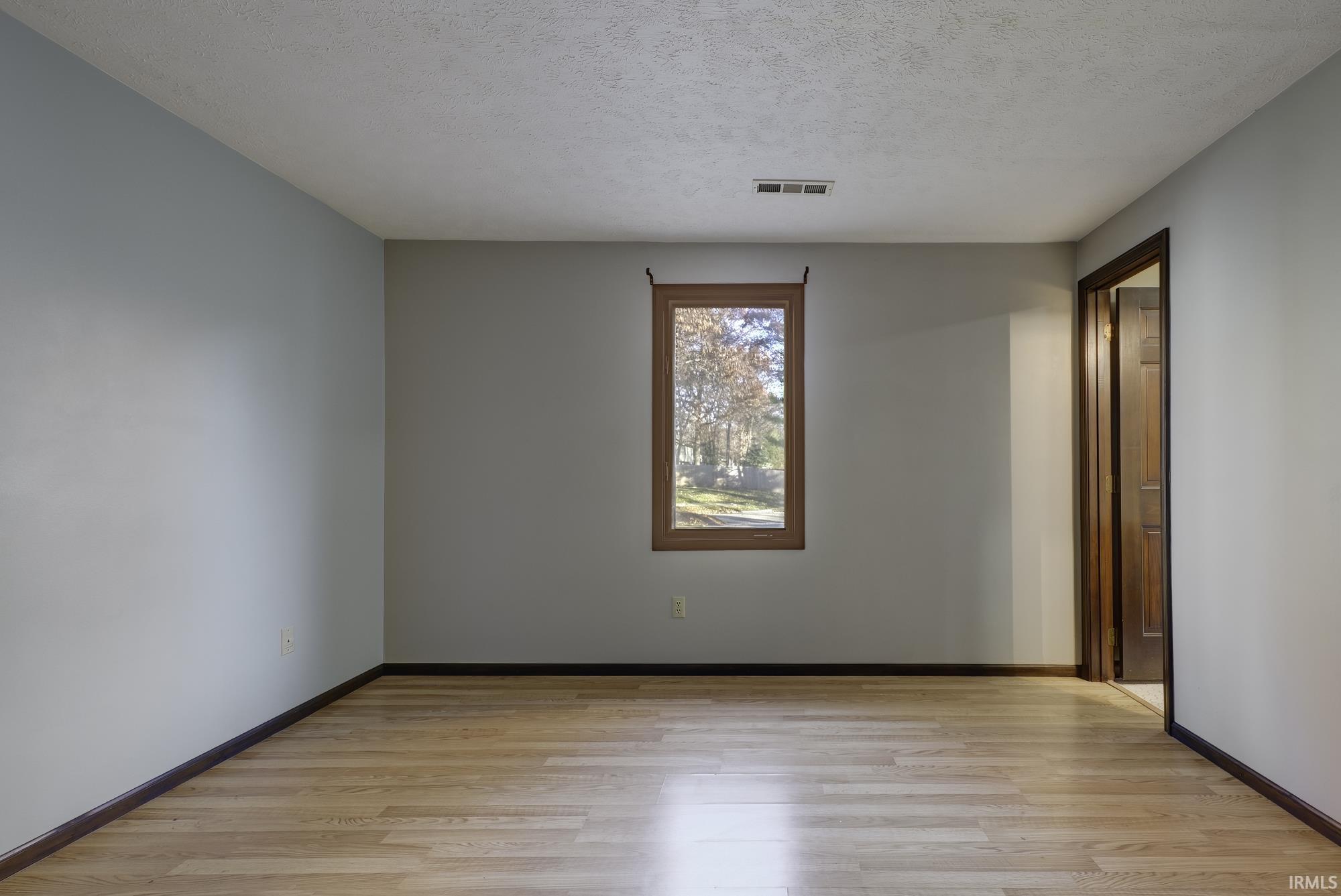 Empty room with light wood-style floors and a textured ceiling