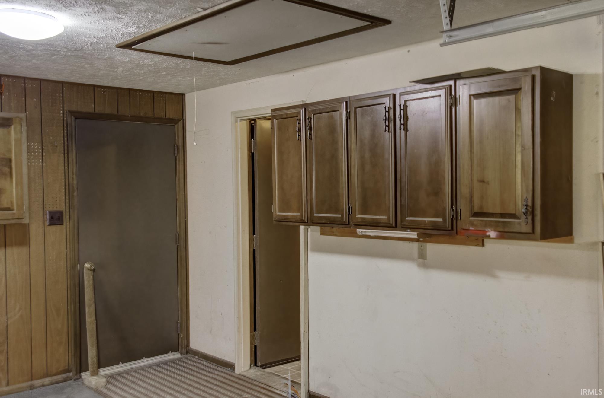 Laundry area featuring attic access, wooden walls, and a textured ceiling
