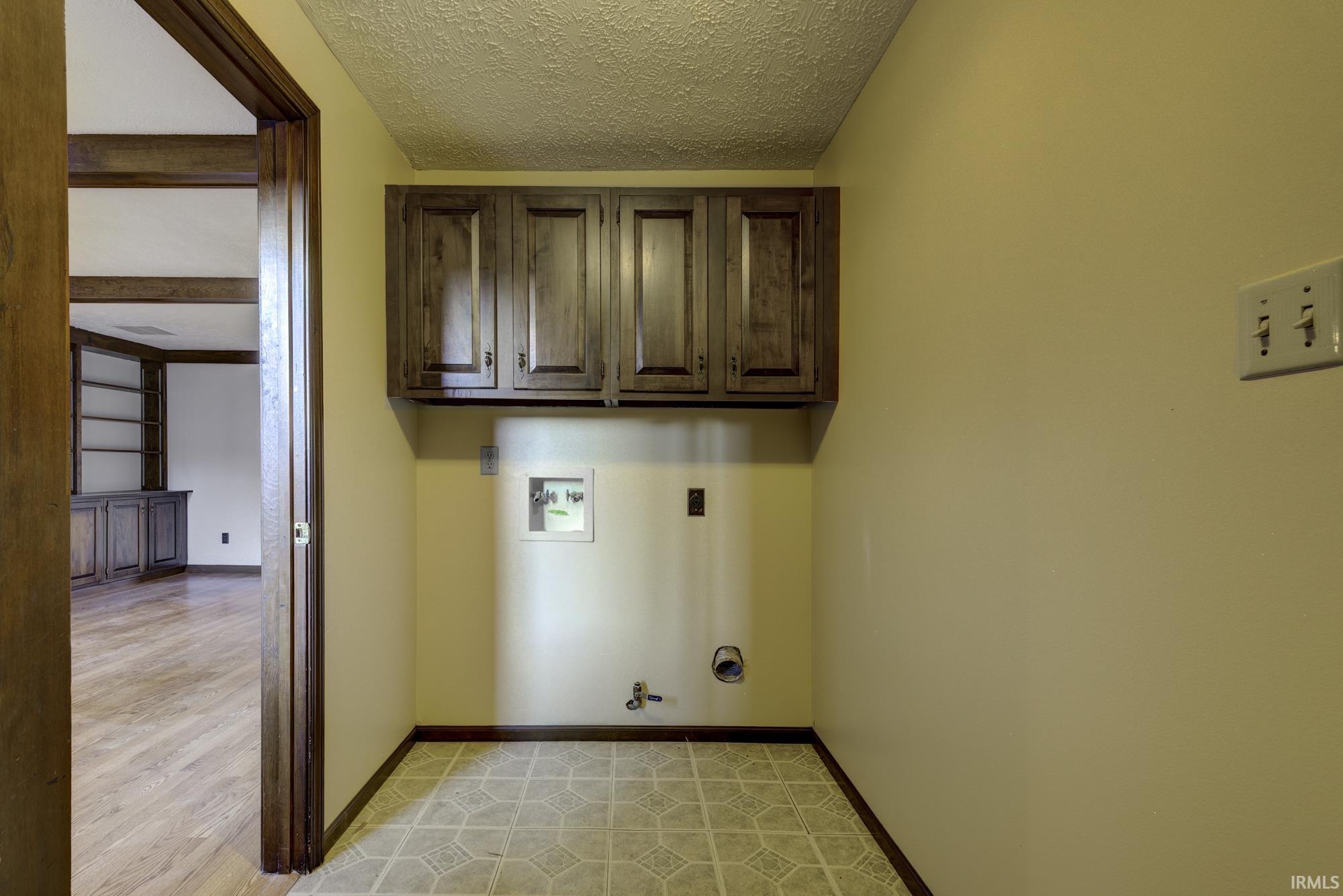 Laundry room with gas dryer hookup, a textured ceiling, washer hookup, cabinet space, and light wood-style flooring