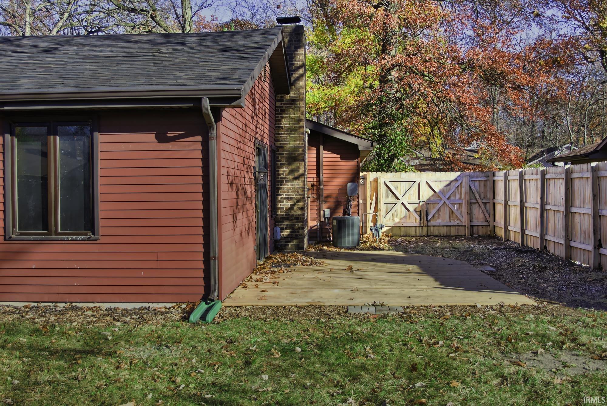 View of property exterior featuring a chimney, a fenced backyard, and a wooden deck