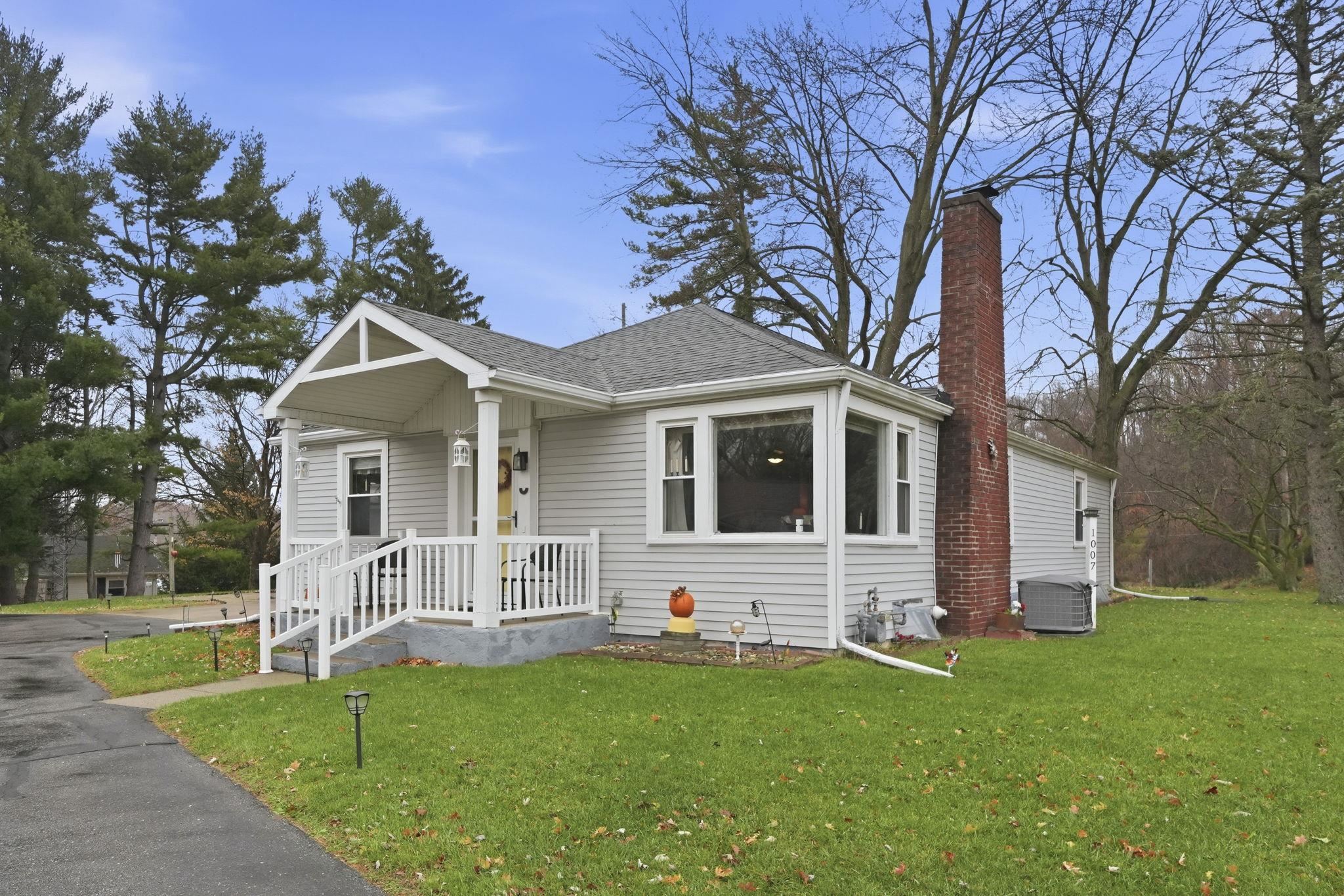 Bungalow featuring a front yard, a shingled roof, and a chimney