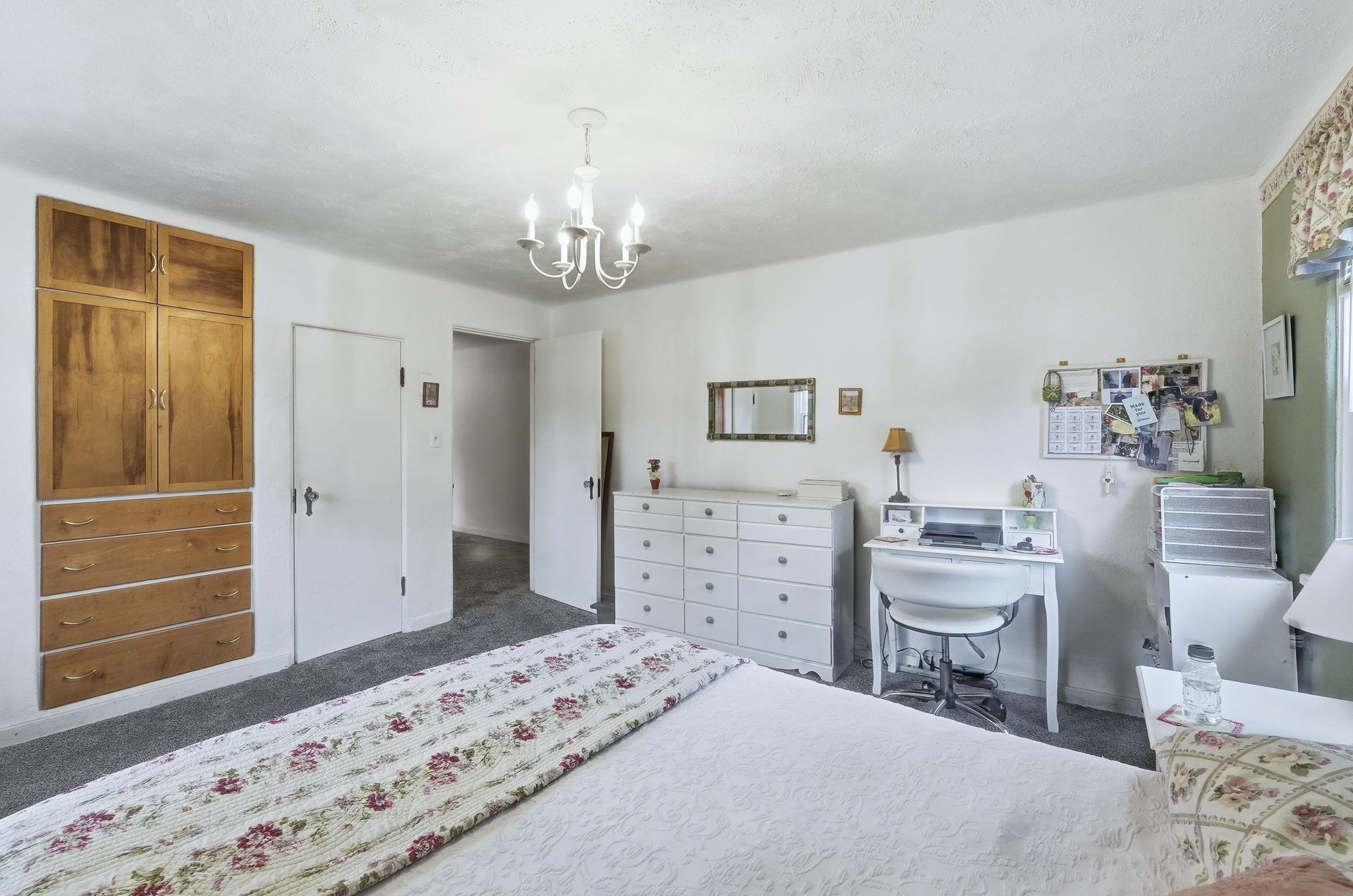 Bedroom with a chandelier, dark carpet, and a desk