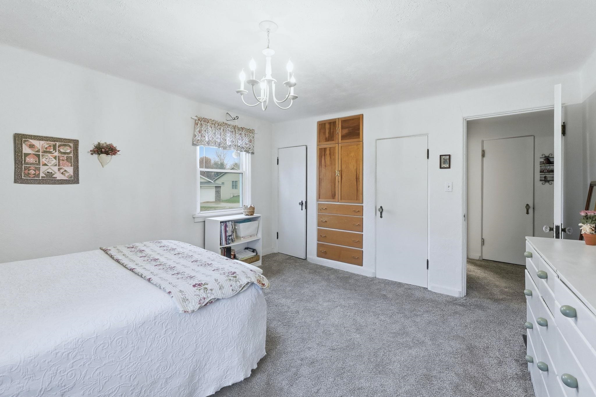 Bedroom featuring light colored carpet, a closet, and a chandelier