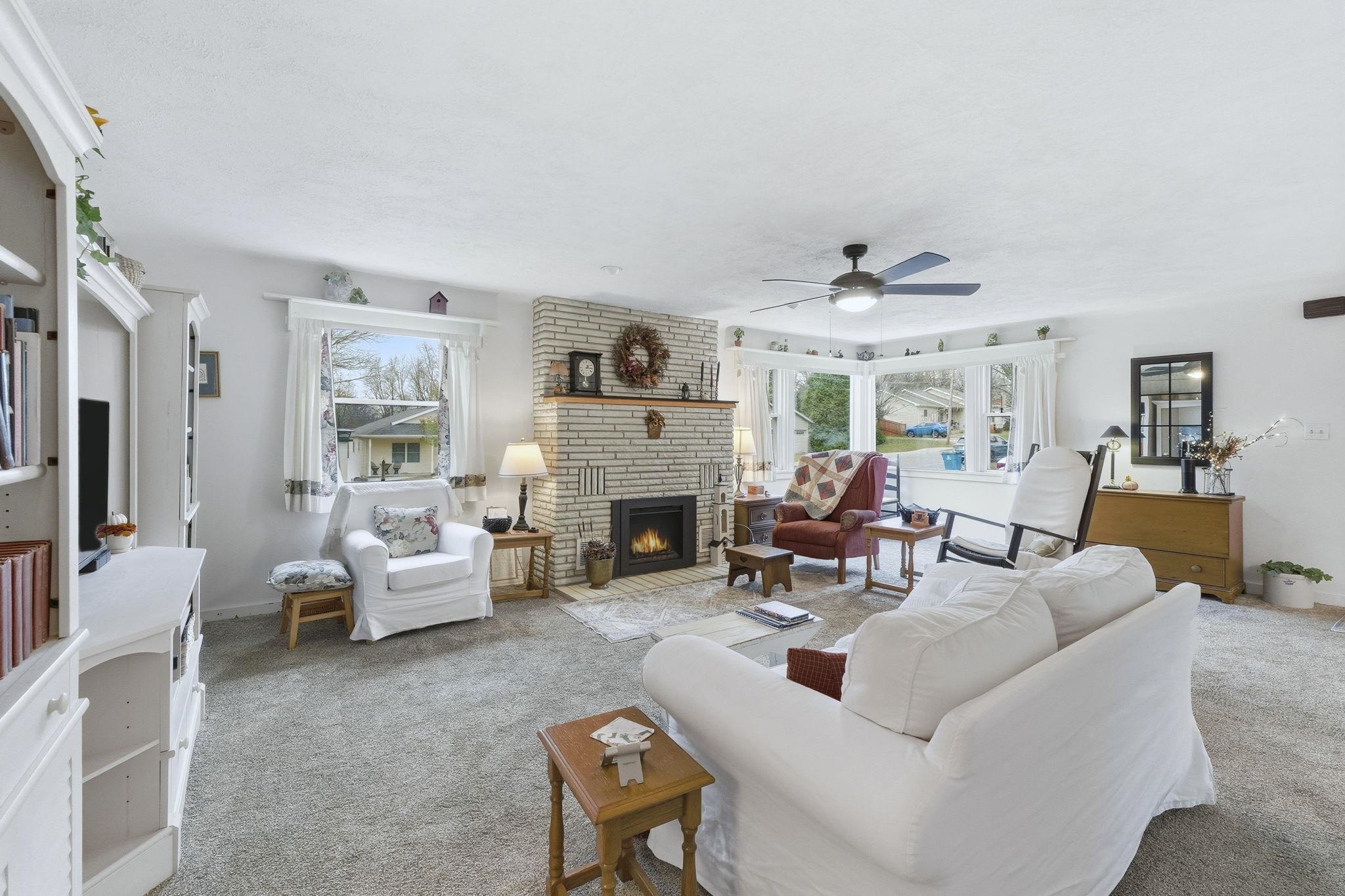 Carpeted living area with a brick fireplace and ceiling fan