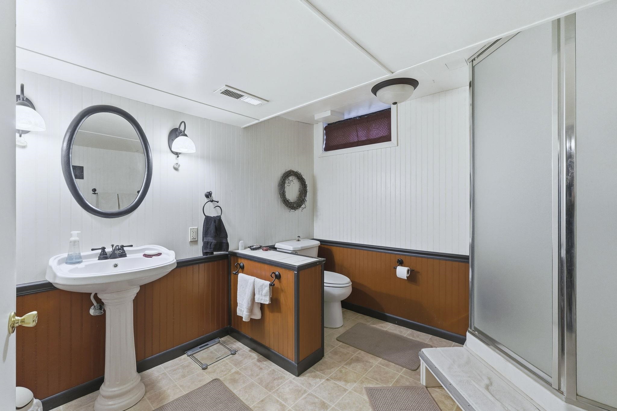 Bathroom with a stall shower, wooden walls, and light tile patterned floors