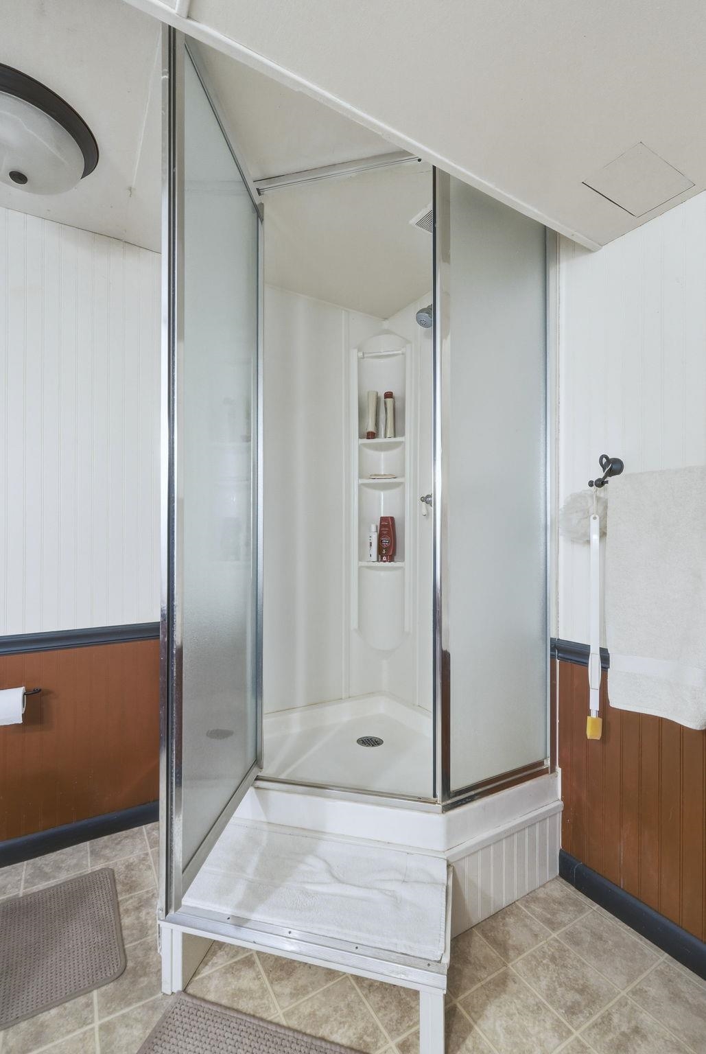 Bathroom featuring wooden walls, a stall shower, and light tile patterned floors