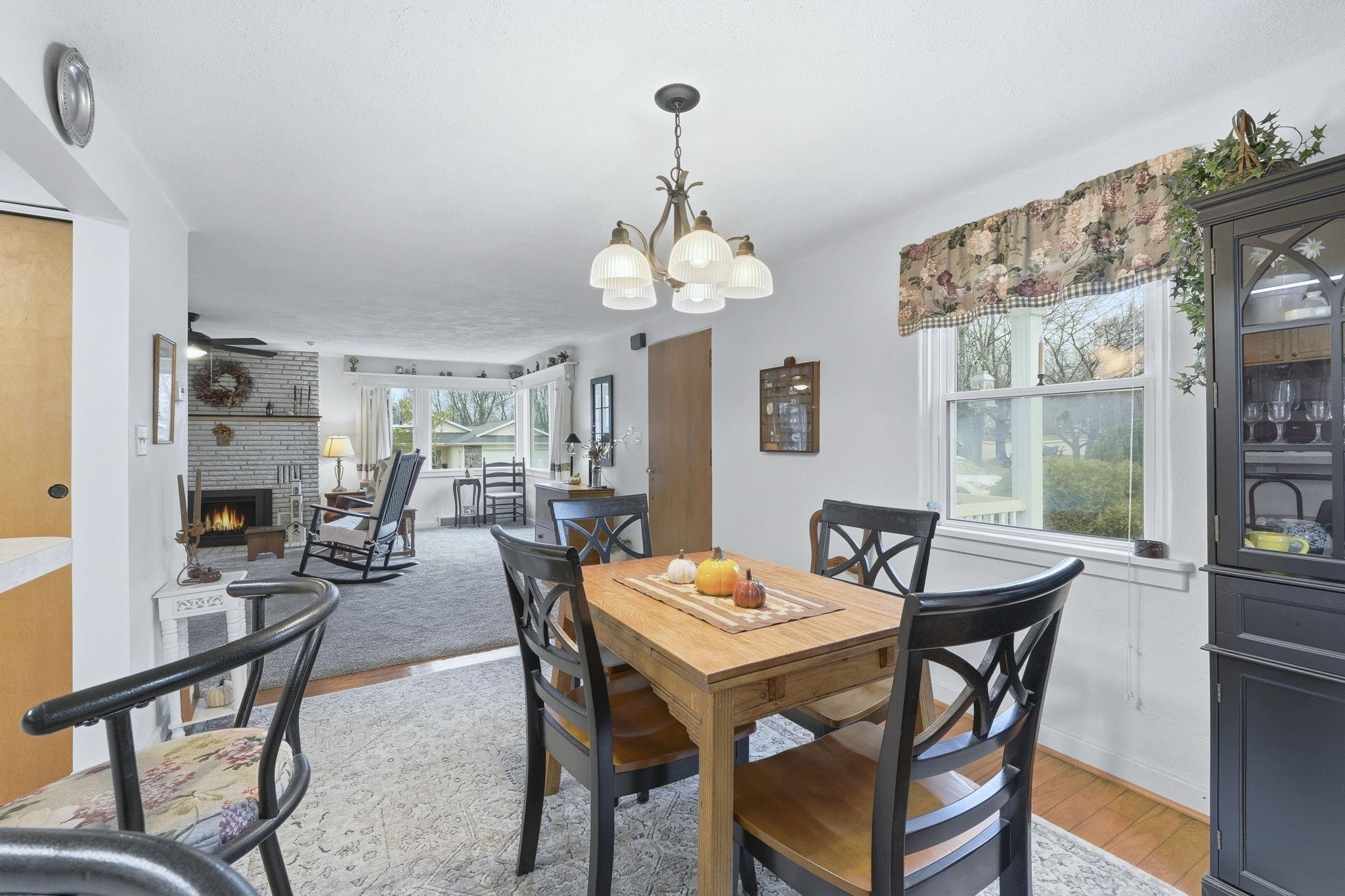 Dining space with a brick fireplace, light wood-type flooring, and a chandelier