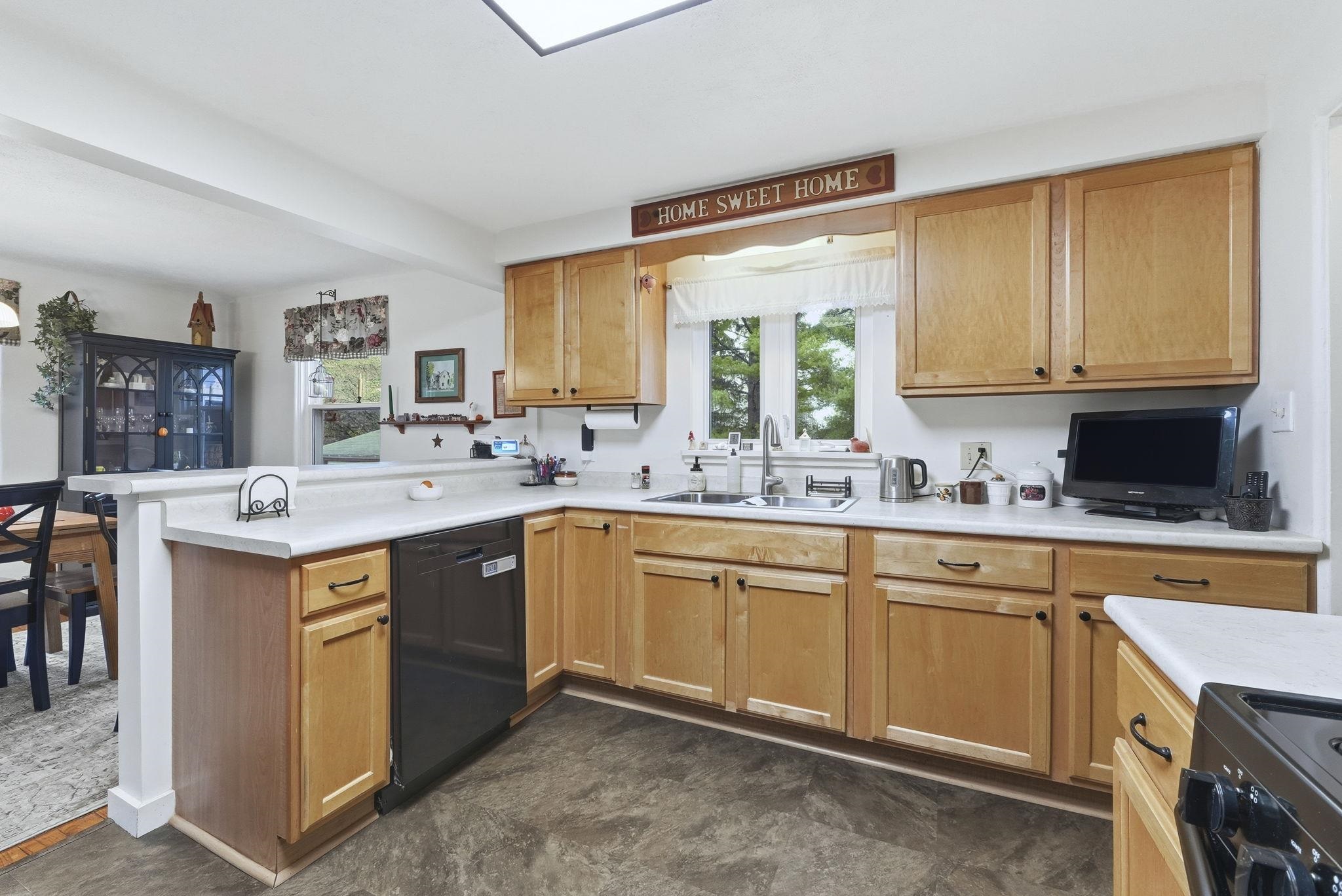 Kitchen featuring a peninsula, light countertops, range, and dishwasher