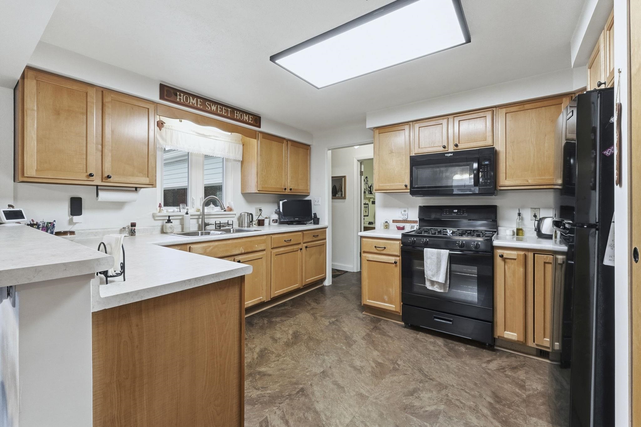 Kitchen featuring light countertops, black appliances, and a peninsula