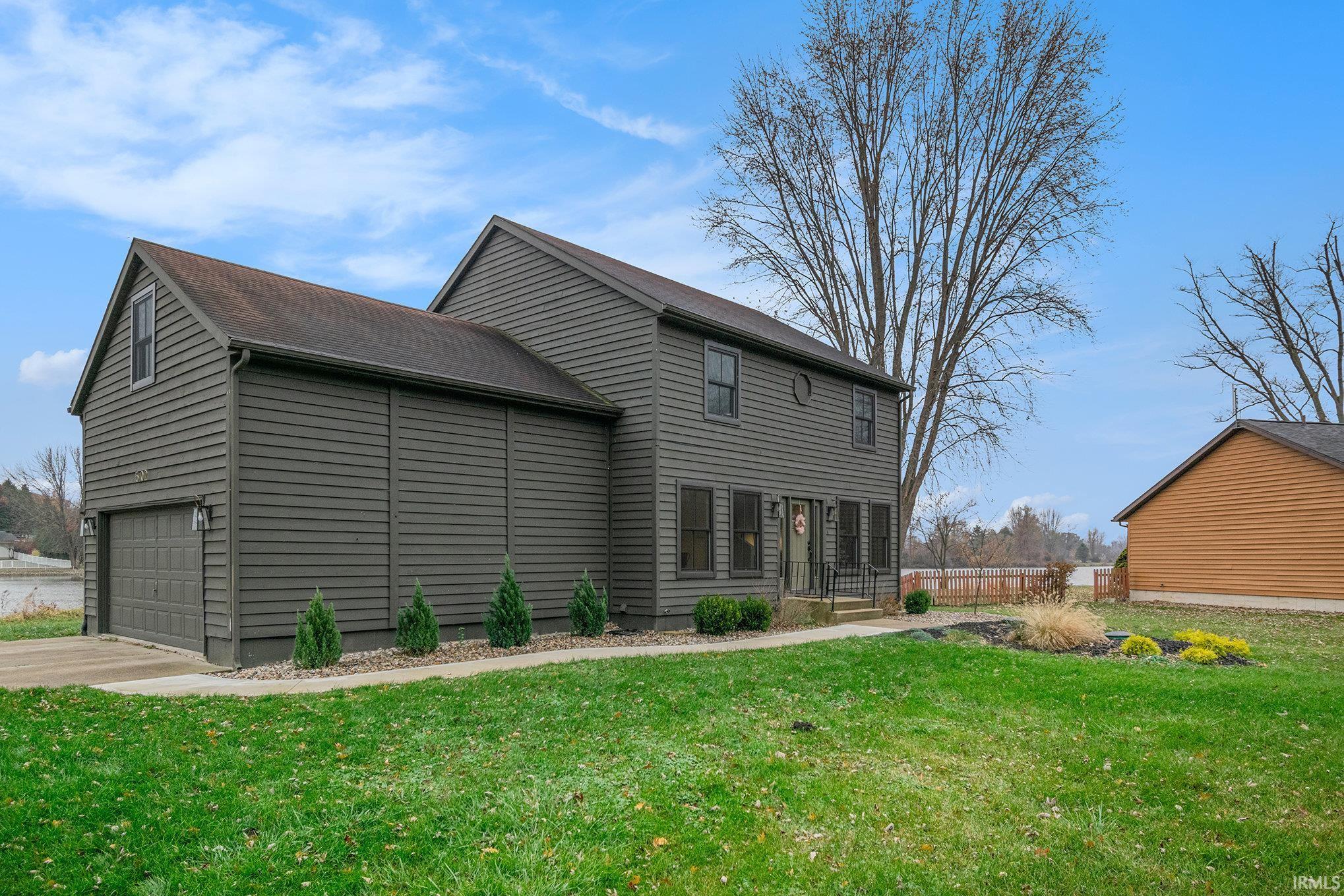 Rear view of house with a lawn, driveway, and a garage