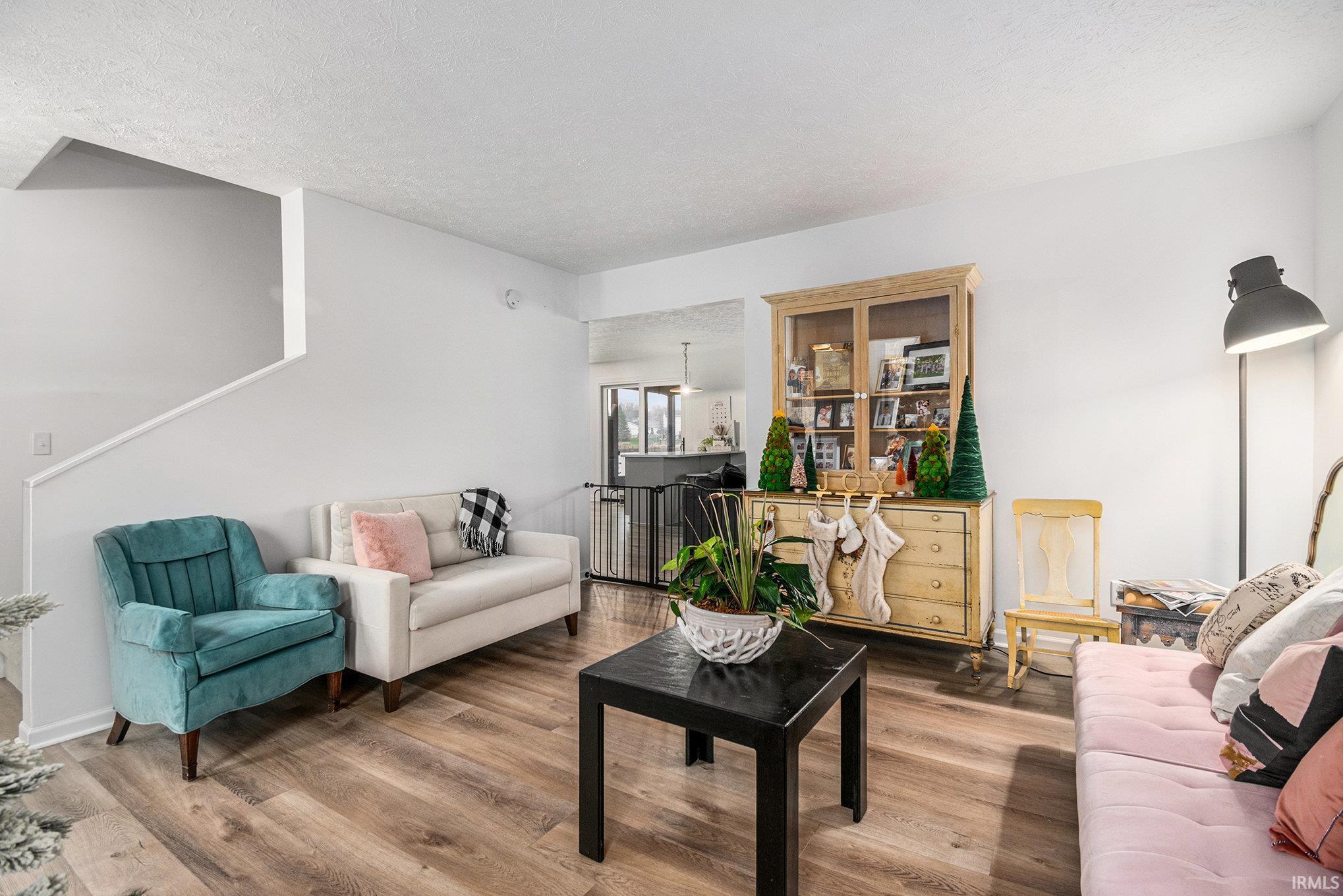 Living area featuring wood finished floors, a textured ceiling, and stairway