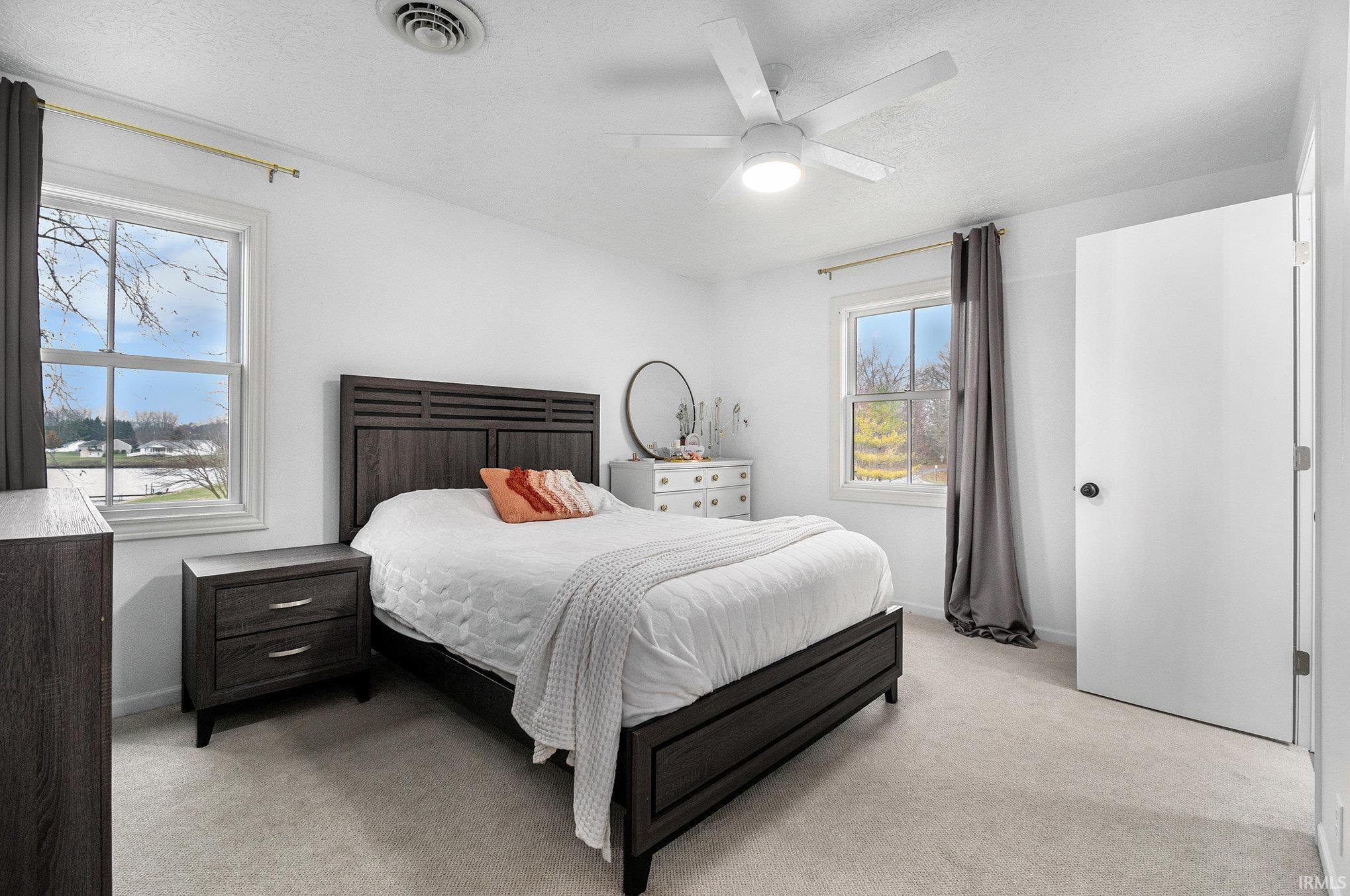Carpeted bedroom with ceiling fan and a textured ceiling